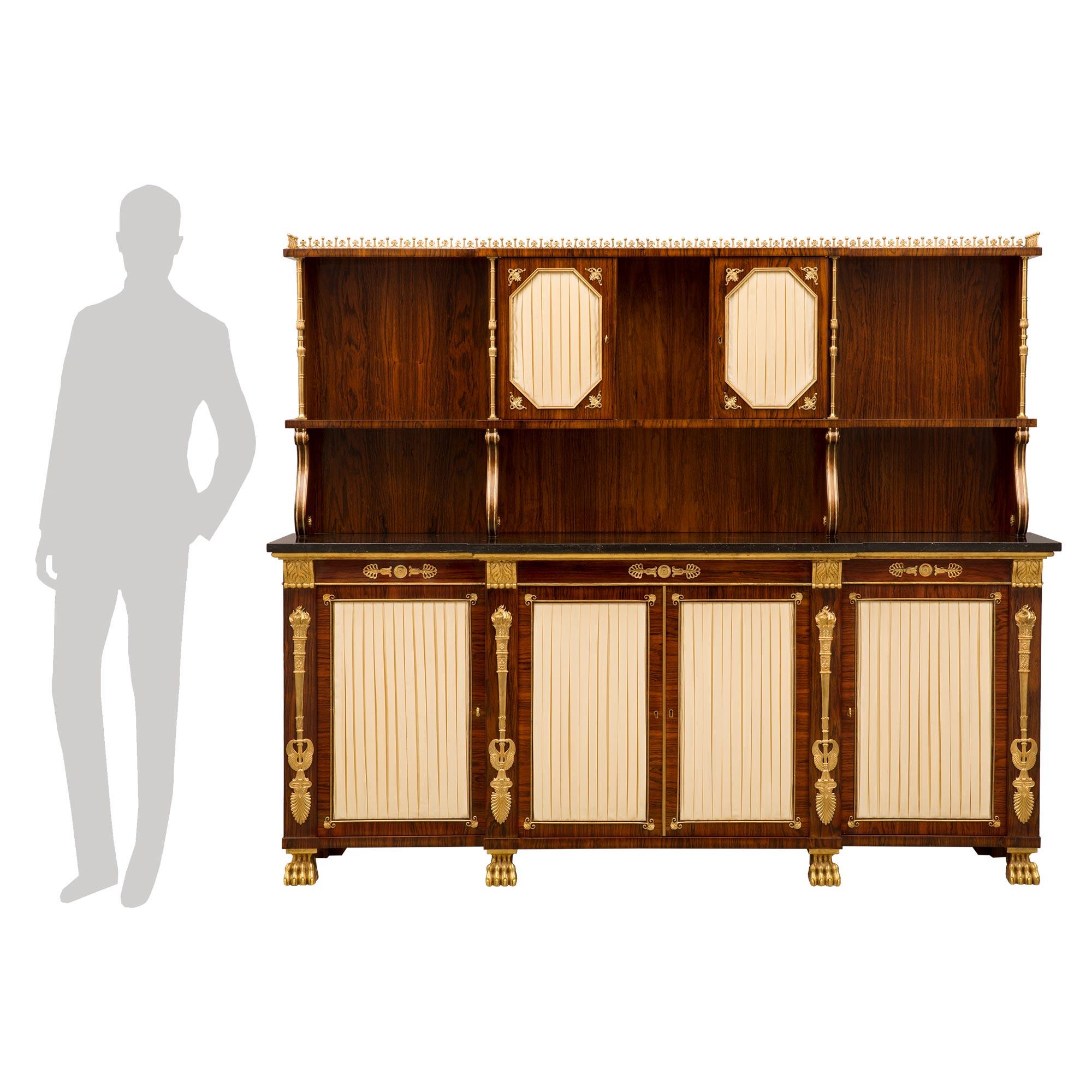A sensational English 19th century Neo Classical st. rosewood, satinwood, giltwood, ormolu and Black Antico marble, Deux Corps buffet. The buffet is raised by handsome giltwood paw feet below the four doors which each retain their original fitted