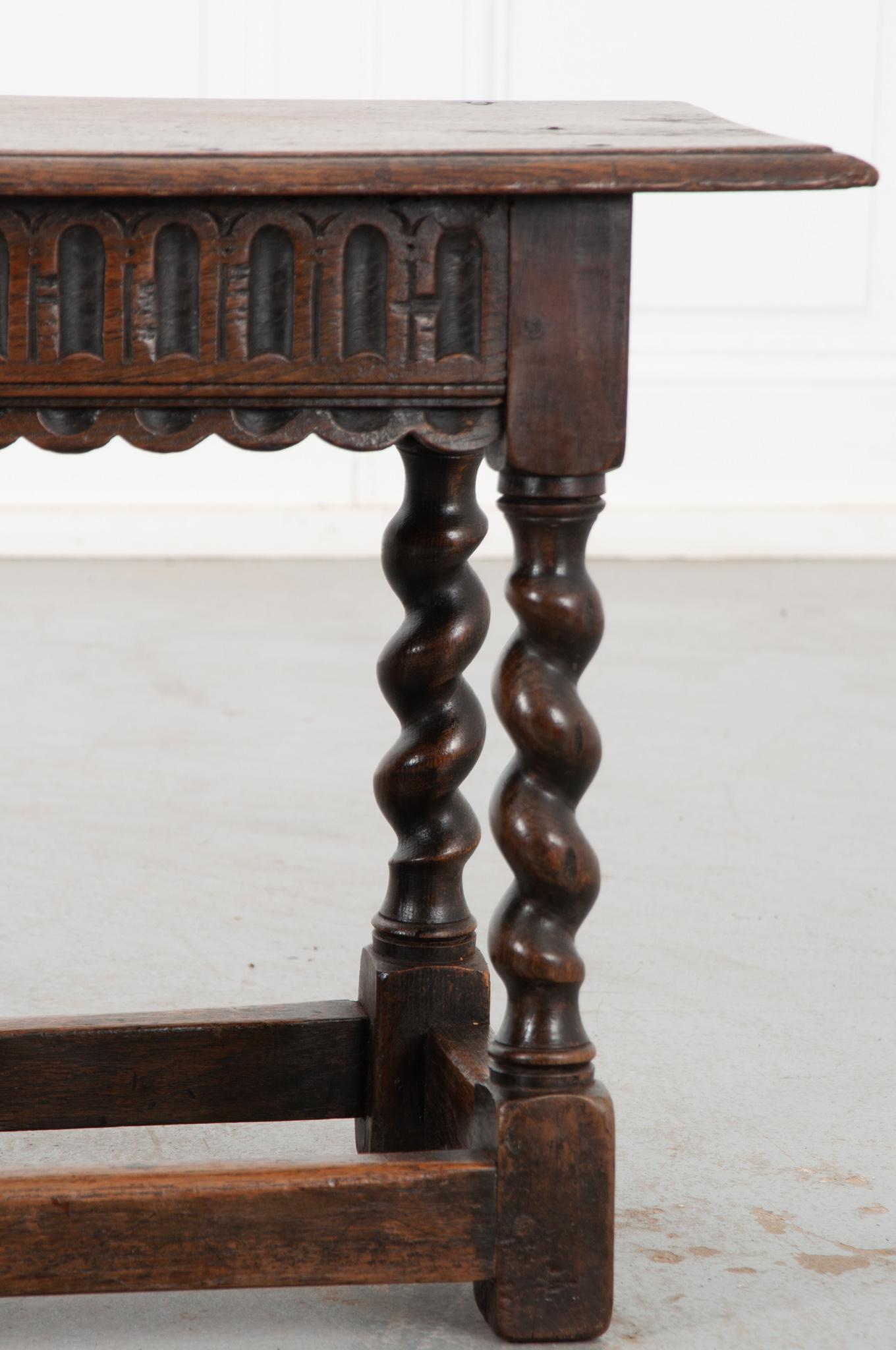 This beautiful dark oak bench is a fine example of 19th century English woodwork. The scalloped apron shows off a cathedral window motif. Six Barley Twist legs support the top of the bench, which has been well used and loved, please make sure to