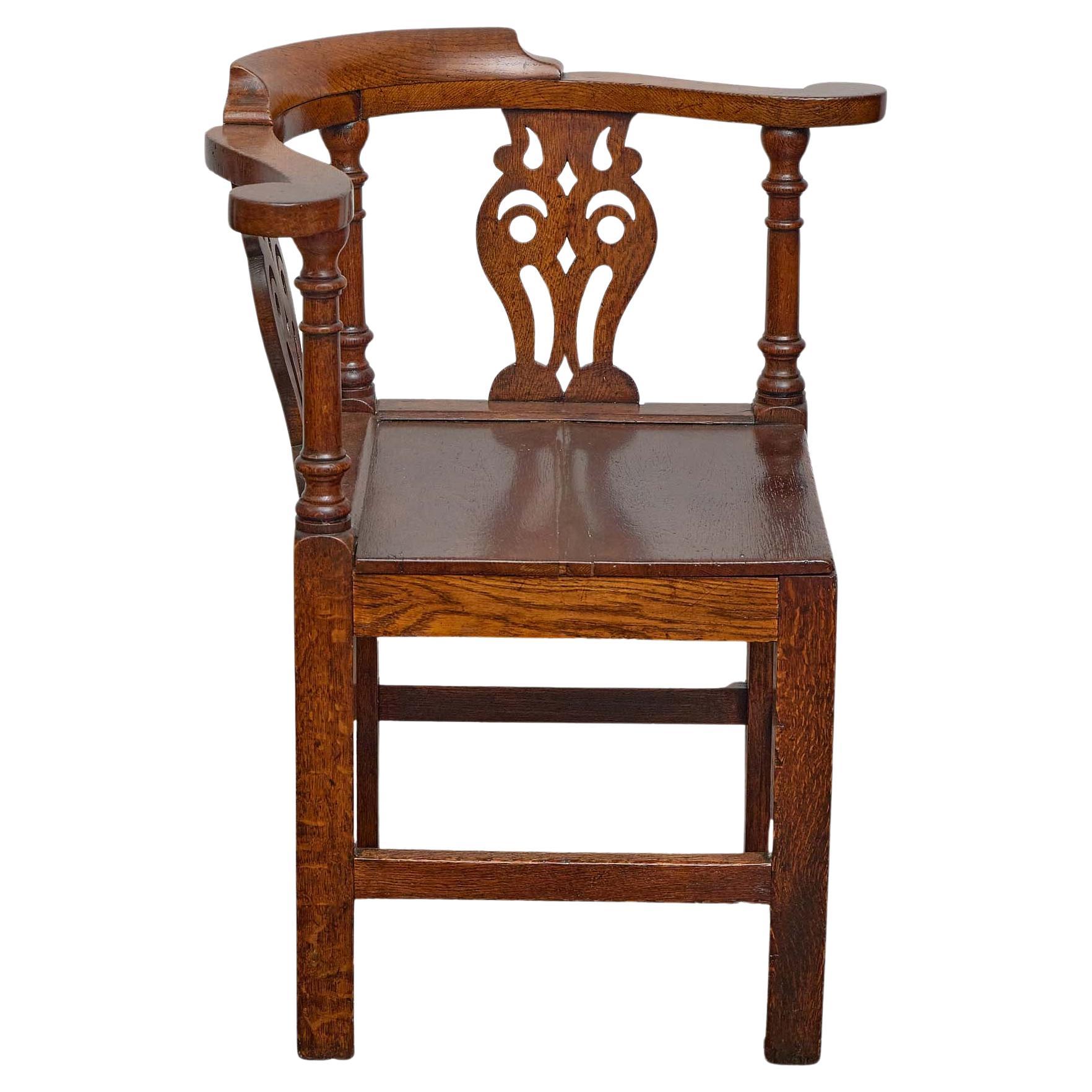 Chaise d'angle anglaise en chêne du XIXe siècle, qui se distingue par sa forme sculpturale et sa fabrication traditionnelle. Conçue avec une assise carrée reposant sur de robustes pieds en bloc reliés par des caissons, la chaise présente un dossier