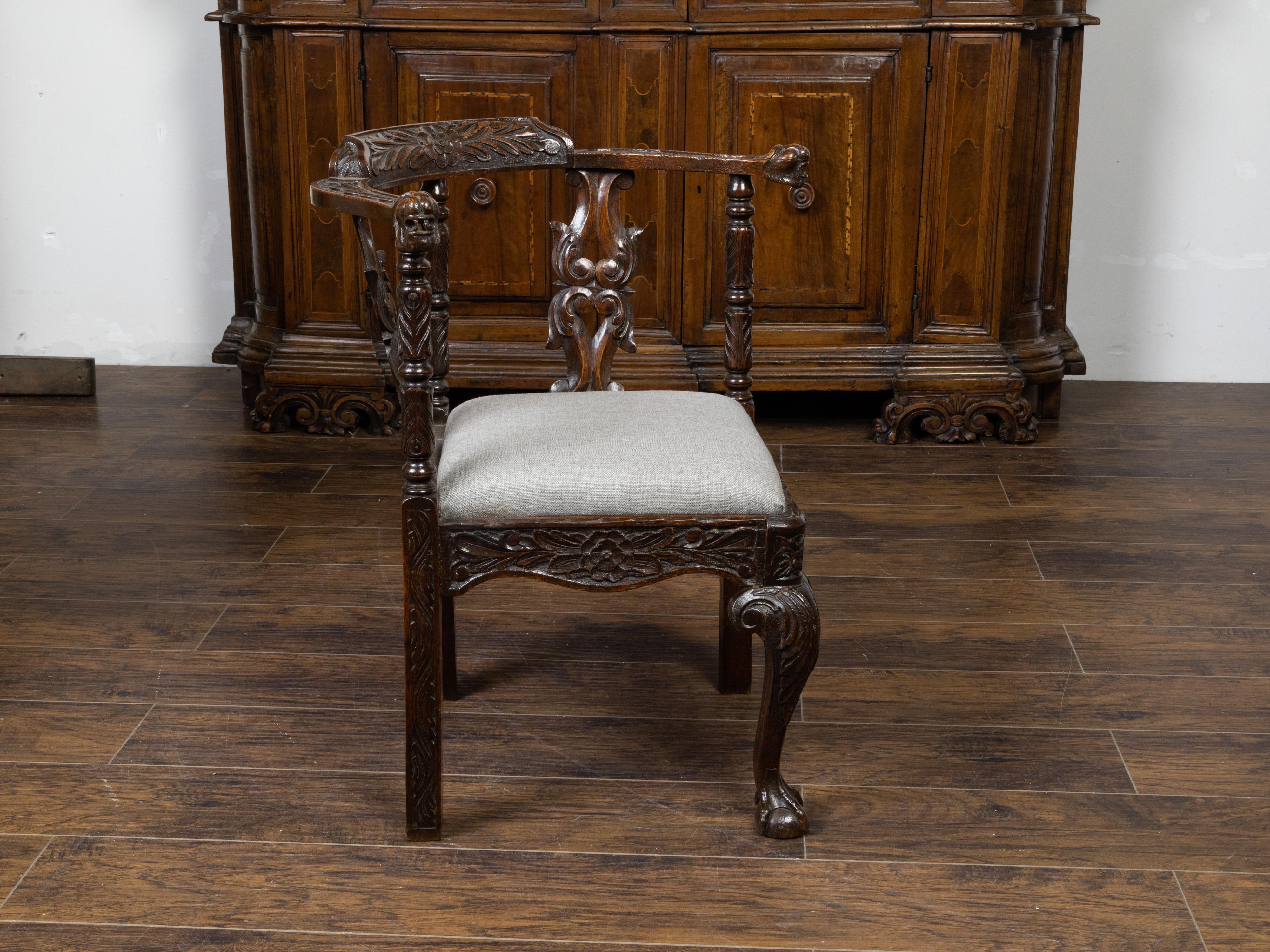 Englischer Eichen-Eckstuhl aus dem 19. Jahrhundert, mit geschnitztem Blattwerk, Maskaron-Motiven und neuer Polsterung. Dieser Eckstuhl aus Eichenholz, der im 19. Jahrhundert in England hergestellt wurde, zeichnet sich durch eine reich geschnitzte