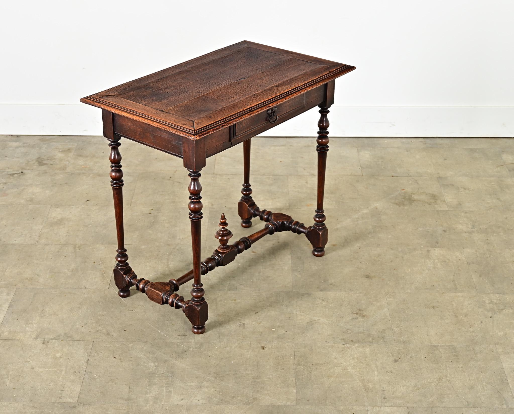 Mesa auxiliar inglesa de roble del siglo XIX, estilo William & Mary, con tablero volado sobre una caja que alberga un pequeño cajón para utilizarla también como pequeña consola o mesa de escritorio ocasional. Al parecerse a mesas auxiliares Luis