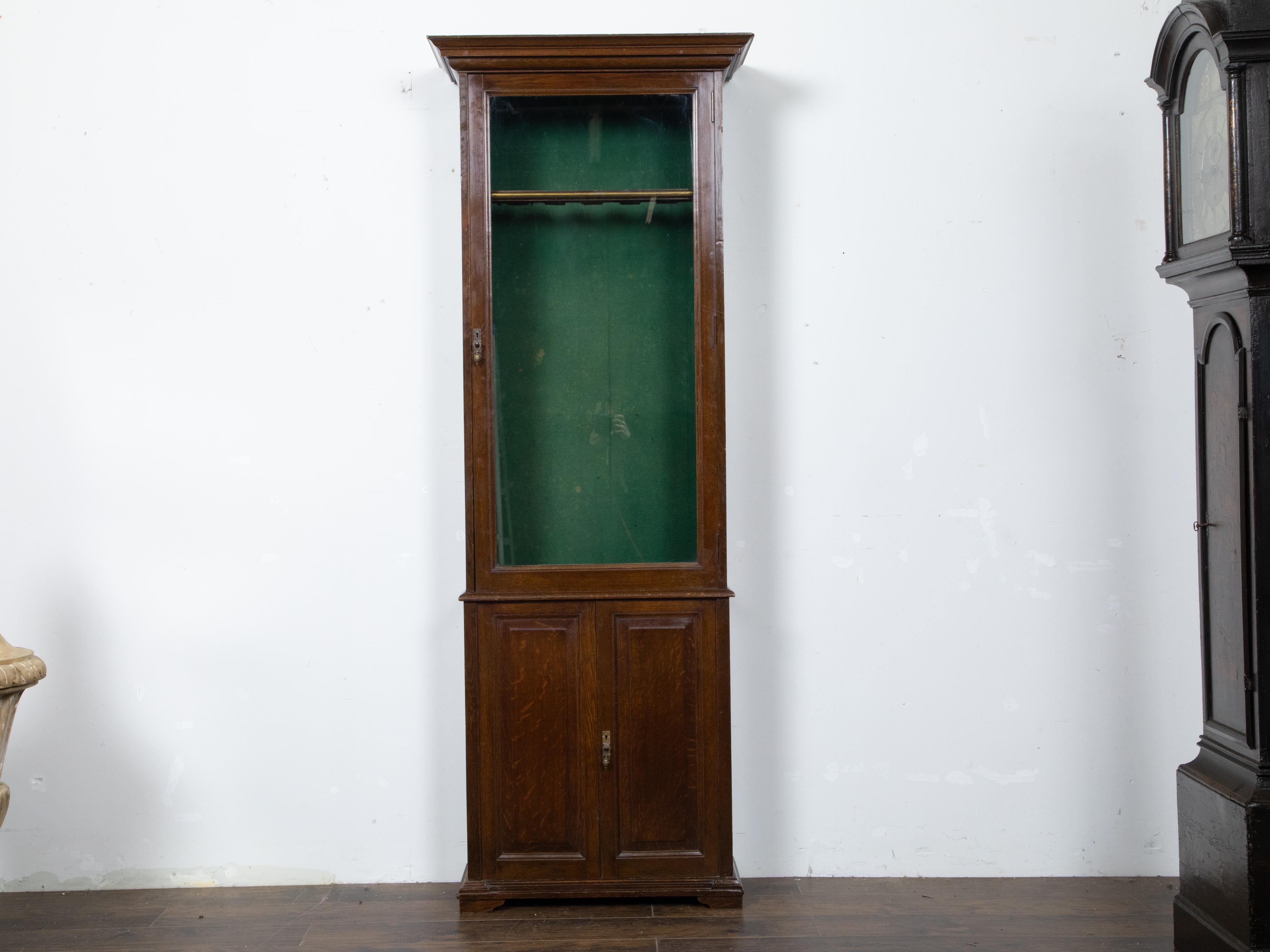An English oak gun cabinet from the 19th century, with single glass door, felt interior, wooden doors and inner drawers. Created in England during the 19th century, this oak gun cabinet features a molded and beveled cornice overhanging a single