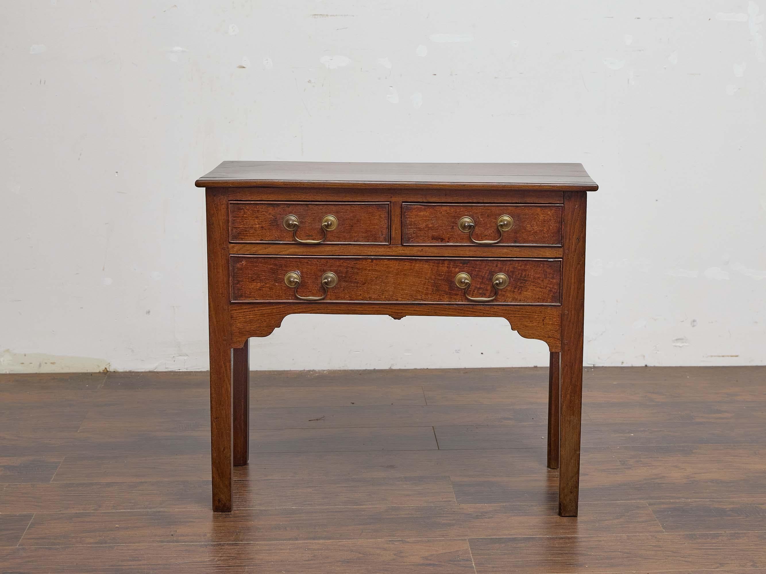 A charming English oak lowboy dating to the 19th century, featuring three drawers and a warm, timeworn patina that speaks to its history. The rectangular top is flat with a softly chamfered edge, resting above two short drawers over a single
