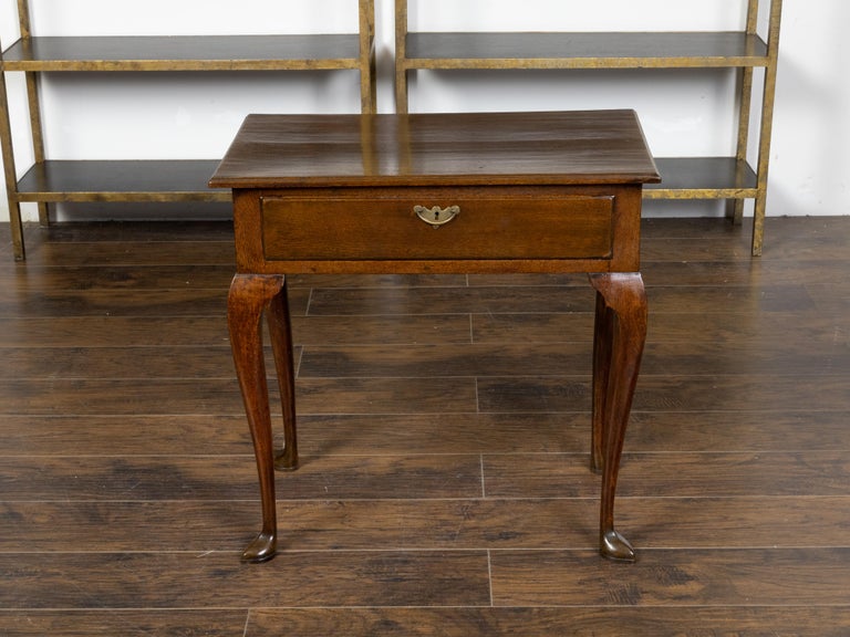 An English oak lowboy table from the 19th century, with single drawer, brass Chippendale style hardware, curving legs and slipper feet. Created in England during the 19th century, this oak table, called a lowboy, features a rectangular single