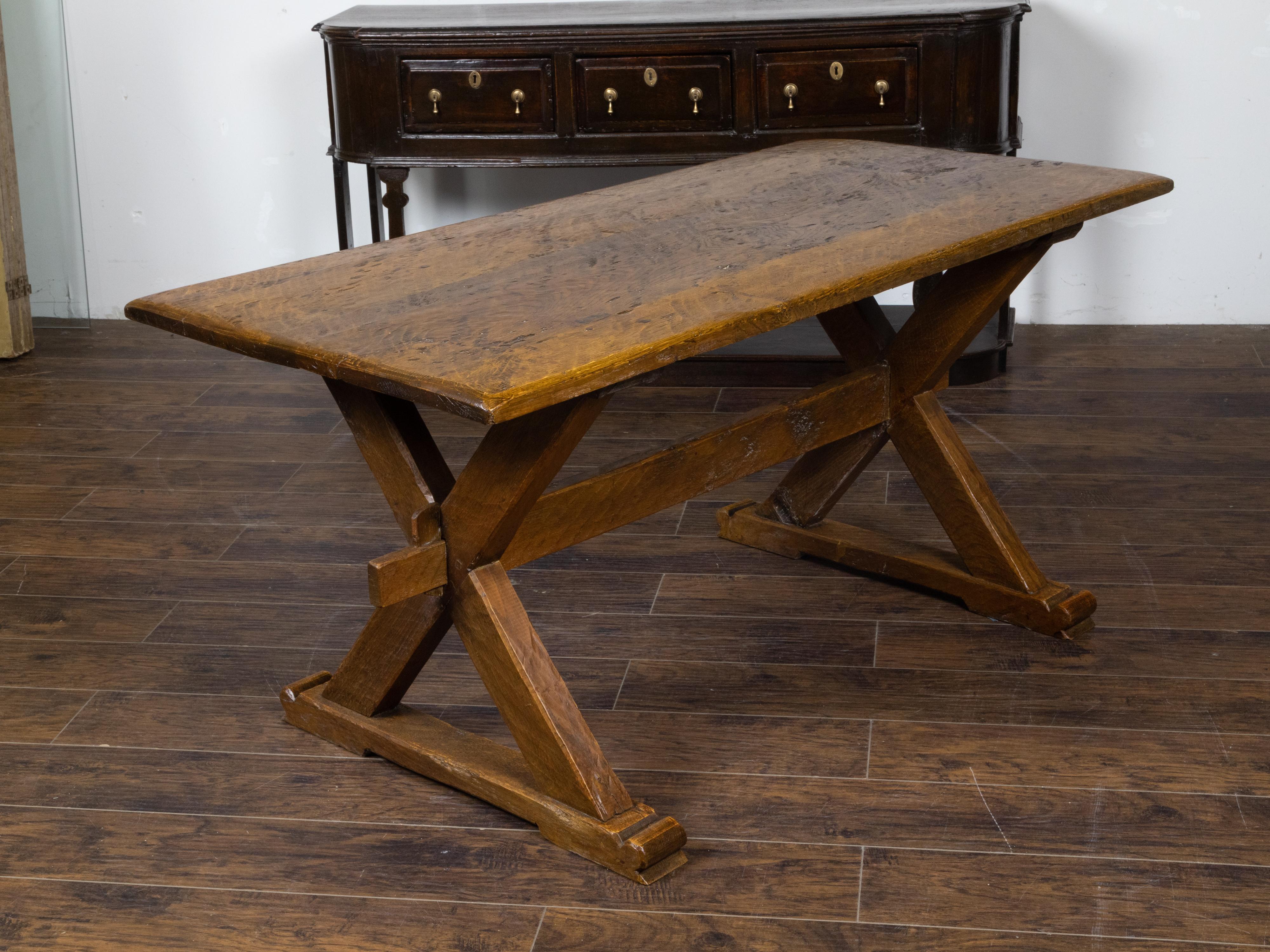 An English oak sawbuck farm table from the 19th century, with double X-Form base, plain cross stretcher and great rustic character. Created in England during the 19th century, this oak sawbuck table features a rectangular planked top with distressed