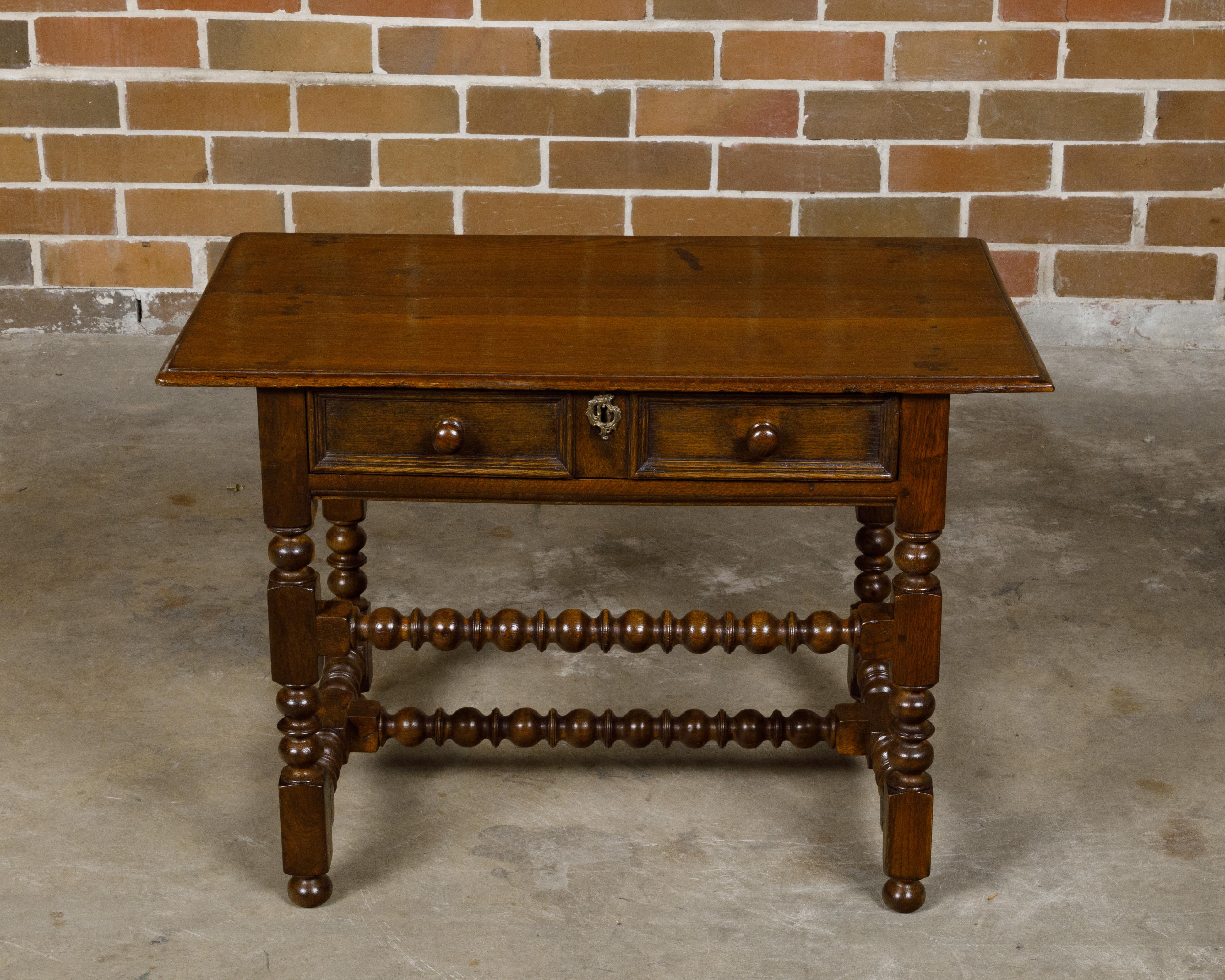 An English bobbin legs oak side table from the 19th century with single drawer and ball feet. Born in England during the 19th century, this oak side table embodies the charm and craftsmanship of its era. The table features a single drawer, adorned