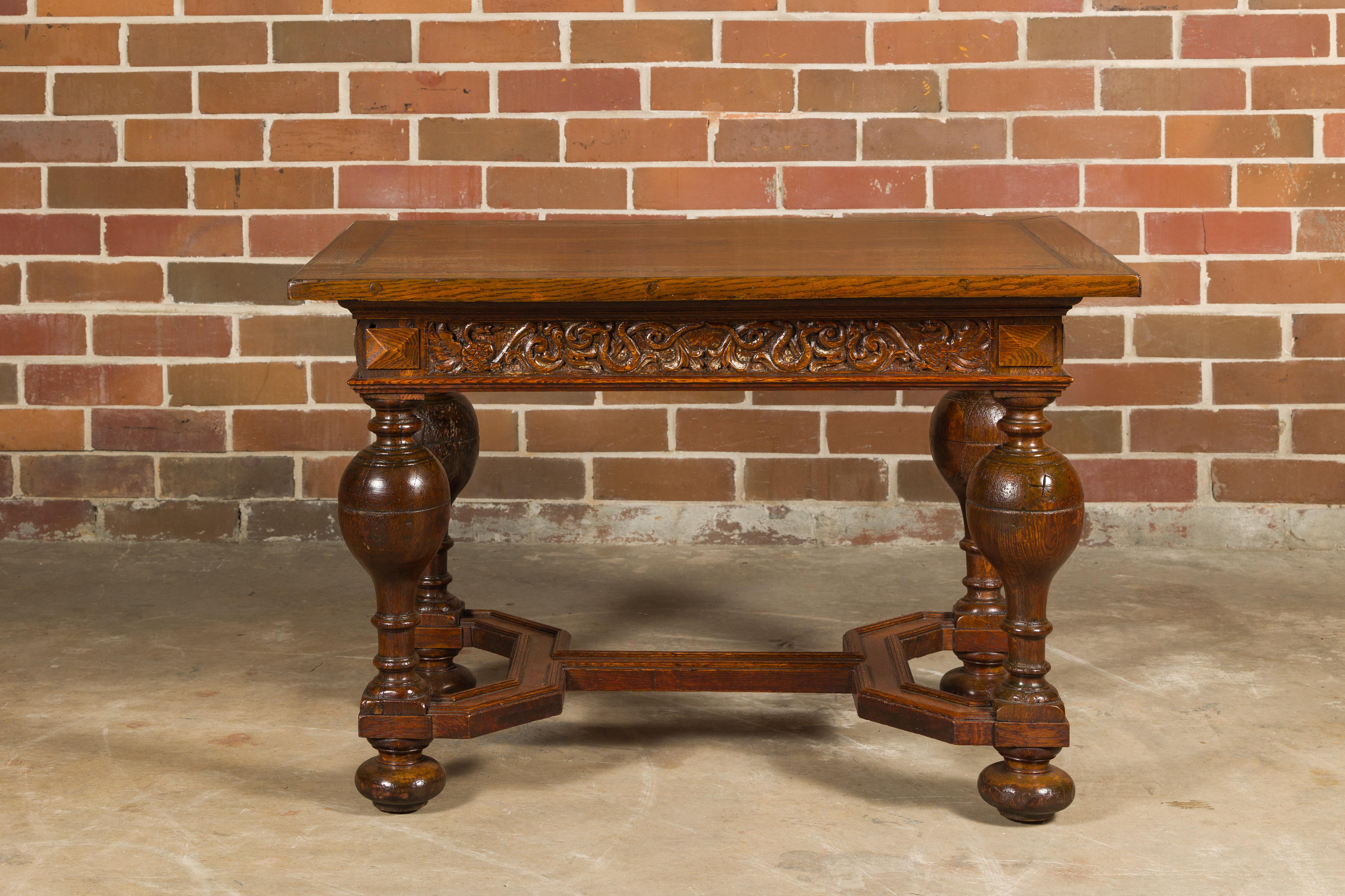 An English oak center table from the 19th century with star-shaped marquetry, carved apron, turned baluster legs and X-Form cross stretcher. This 19th-century English oak center table is a masterpiece of craftsmanship and design. Its star-shaped