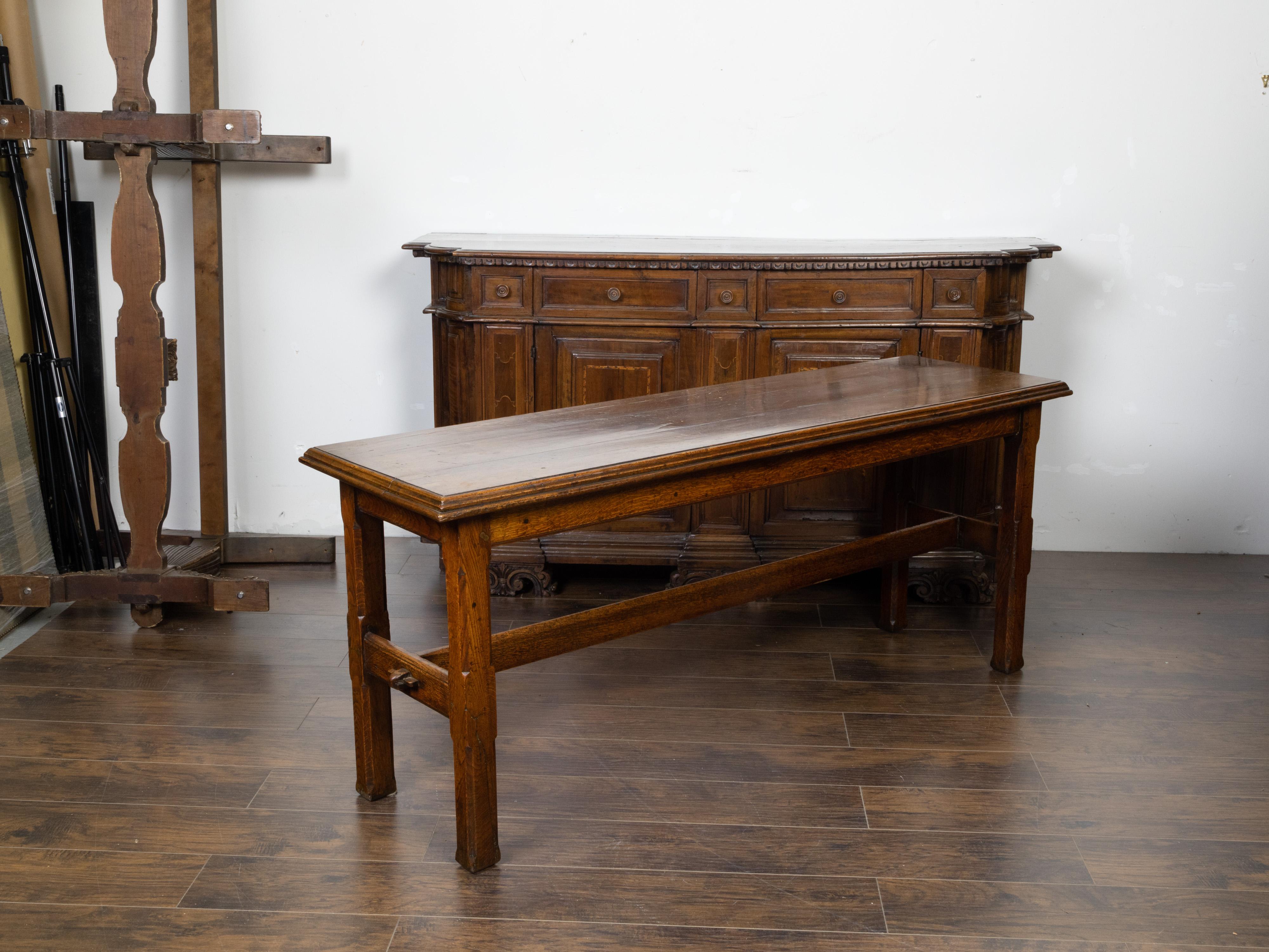 An English oak console table from the 19th century, with straight legs and H-Form cross stretcher. Created in England during the 19th century, this oak table features a rectangular top with stepped edges, sitting above four straight legs with