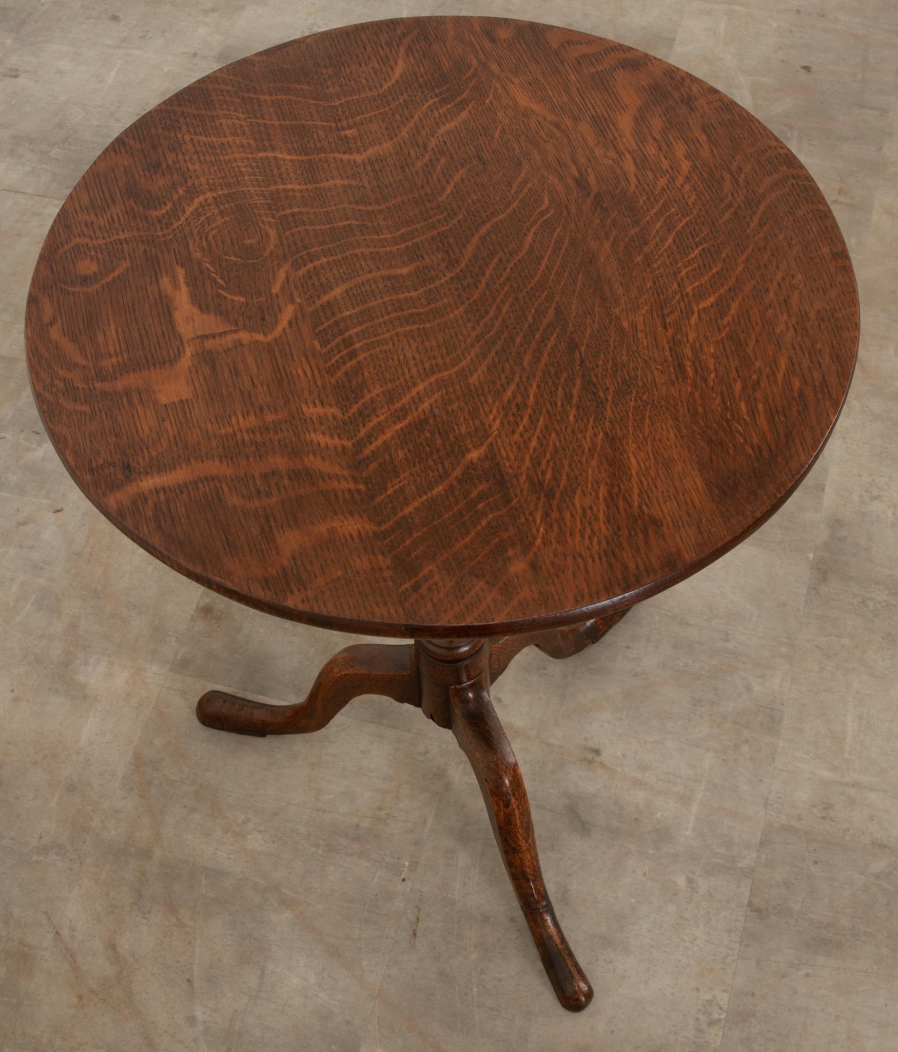 This English tilt top table was crafted from solid oak circa 1820. Simply constructed with a fantastic patina, the top tilts up to be 37-?”H x 20”W x 18”D when you need more space. The turned middle support connects to tripodal feet, giving it a