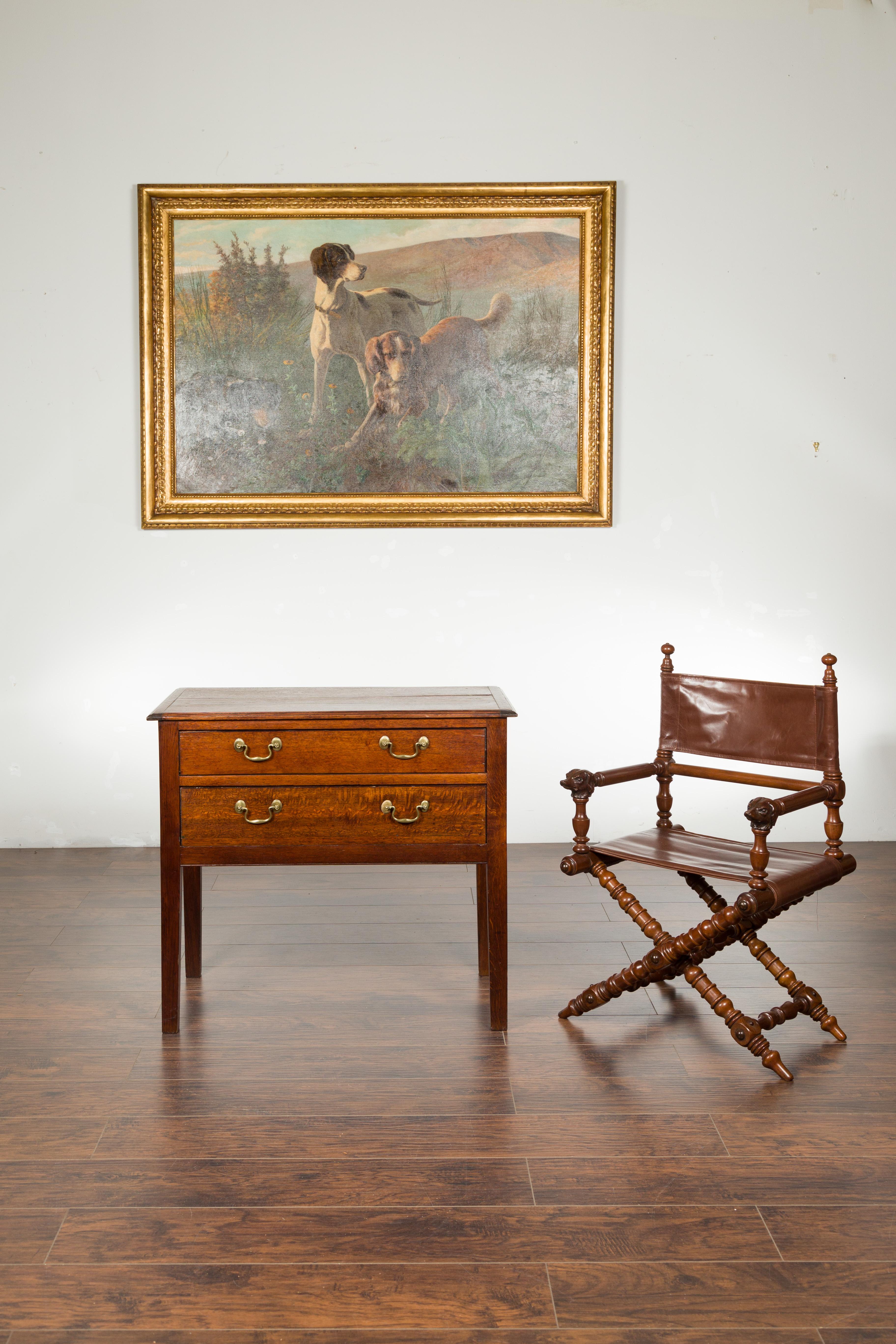 An English oak two-drawer chest from the 19th century, with brass pulls and straight legs. Created in England during the 19th century, this oak chest features a rectangular planked top sitting above two drawers fitted with brass hardware. Raised on