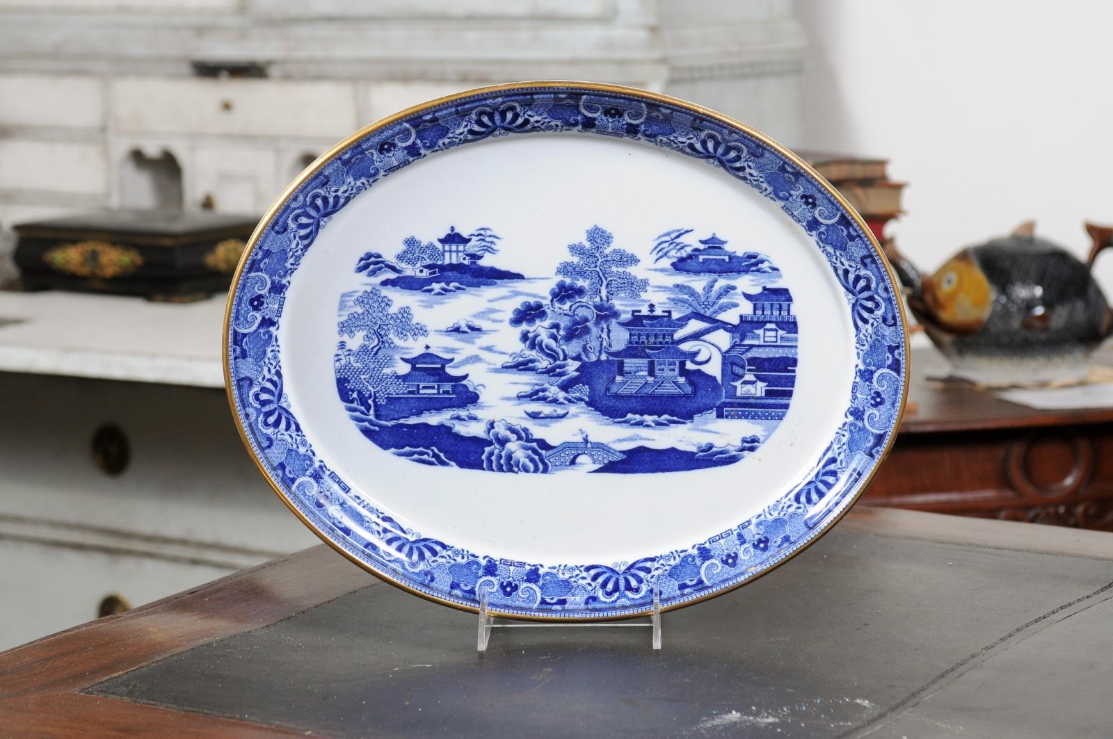 An English blue and white oval porcelain platter from the 19th century, with Chinoiserie motifs. Created in England during the 19th century, this porcelain platter features a white ground perfectly highlighted by a Chinoiserie pattern. Traditional