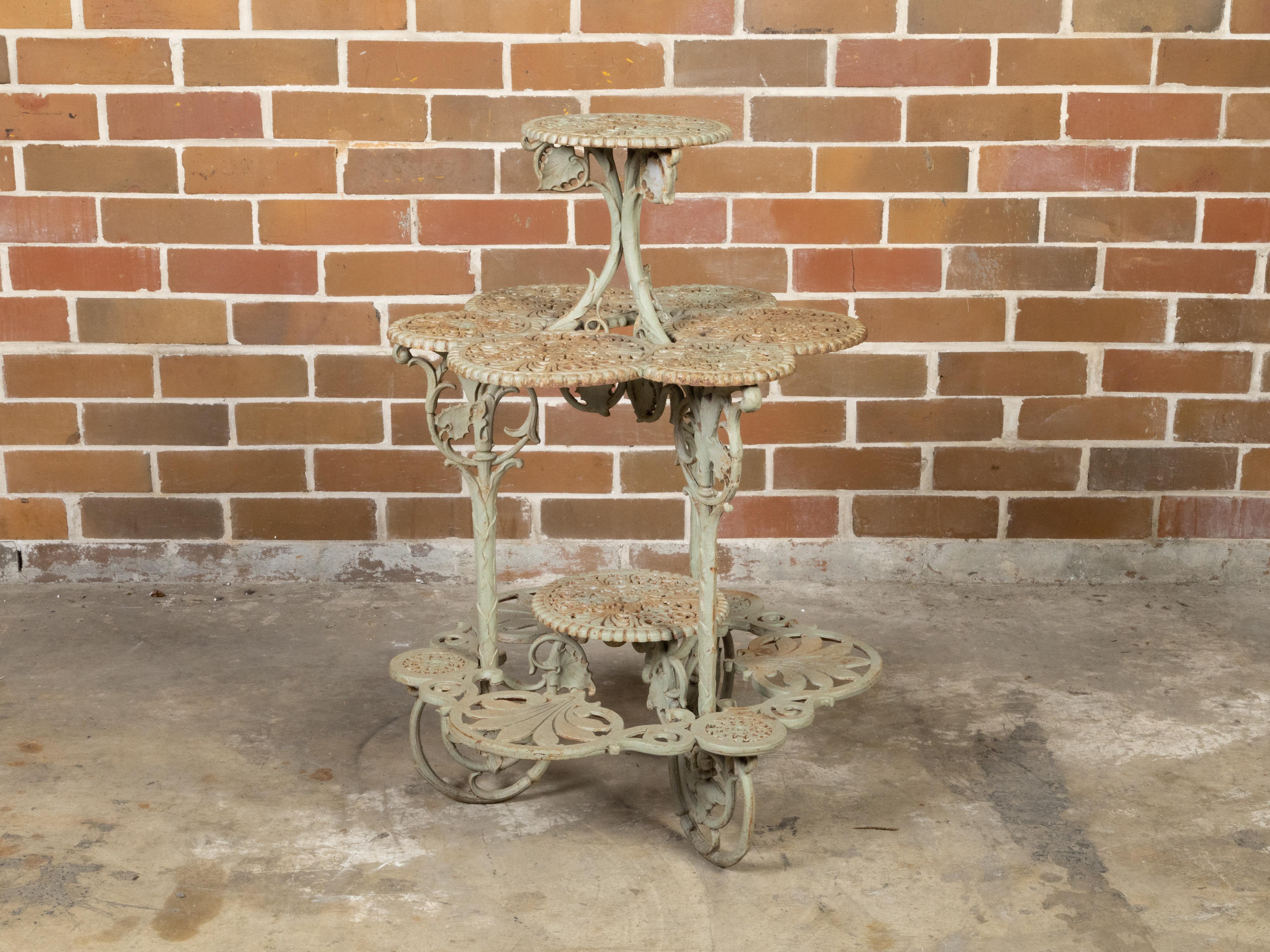 An English iron tiered table from the 19th century with four levels, circular openwork sections and large scrolling feet. Created in England during the 19th century, this uncommon iron tiered table features a circular pierced top adorned with ornate