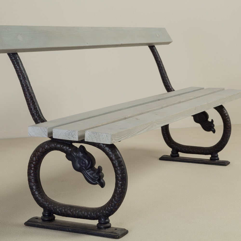 An English 19th century patinated cast iron and wooden bench circa 1860-1880. The iron ends are stylized as serpents with a dark patination.