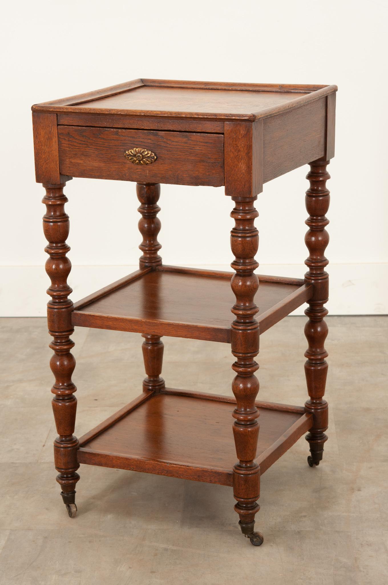 A darling petite etagere from England, crafted circa 1870 from solid oak. Two lower tiers are connected to beautifully turned and styled upright supports. Featuring its original casters, it has the ability to turn 360 degrees. Great for adding a bit