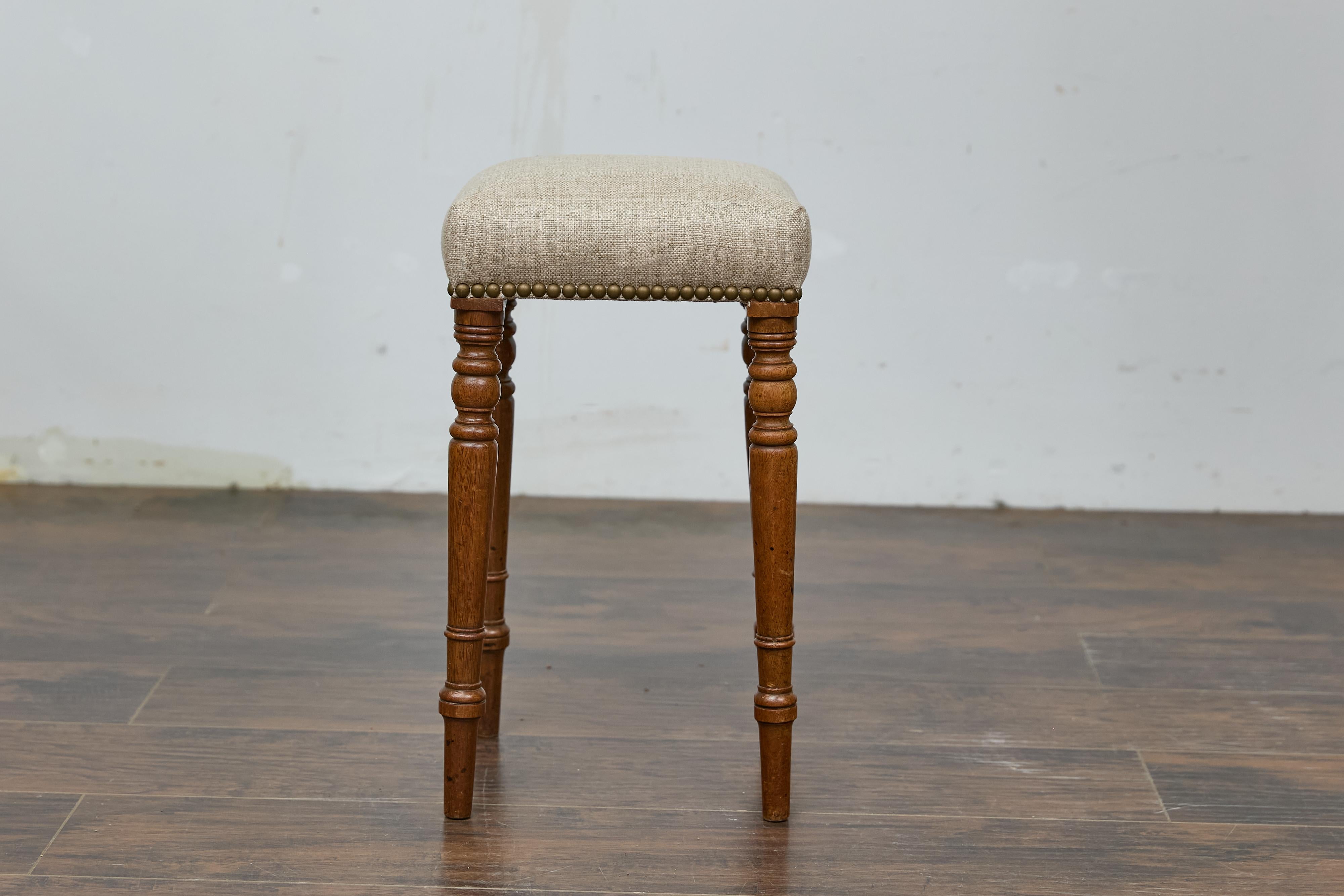Sgabello inglese in legno di quercia del XIX secolo con imbottitura in lino personalizzata e gambe tornite. Lo sgabello è rivestito in lino di alta qualità, che aggiunge al suo fascino rustico un comfort raffinato e un tocco di ricercatezza. Le