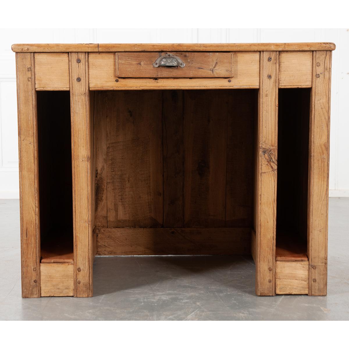 This is a simple English 19th century pine shop counter from an auctioneer in Alsace! Complete with a hole for accepting cash payments inside the drawer. The desk is flanked with tall open storage spaces which would have held ledger books. A very