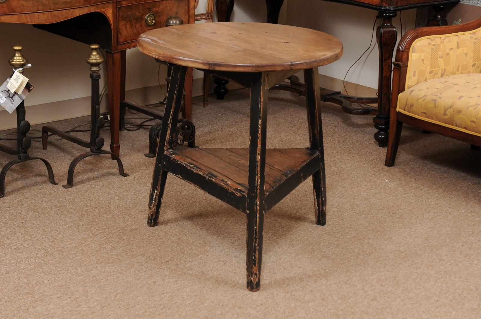 An English round pine and black painted cricket table with lower shelf.