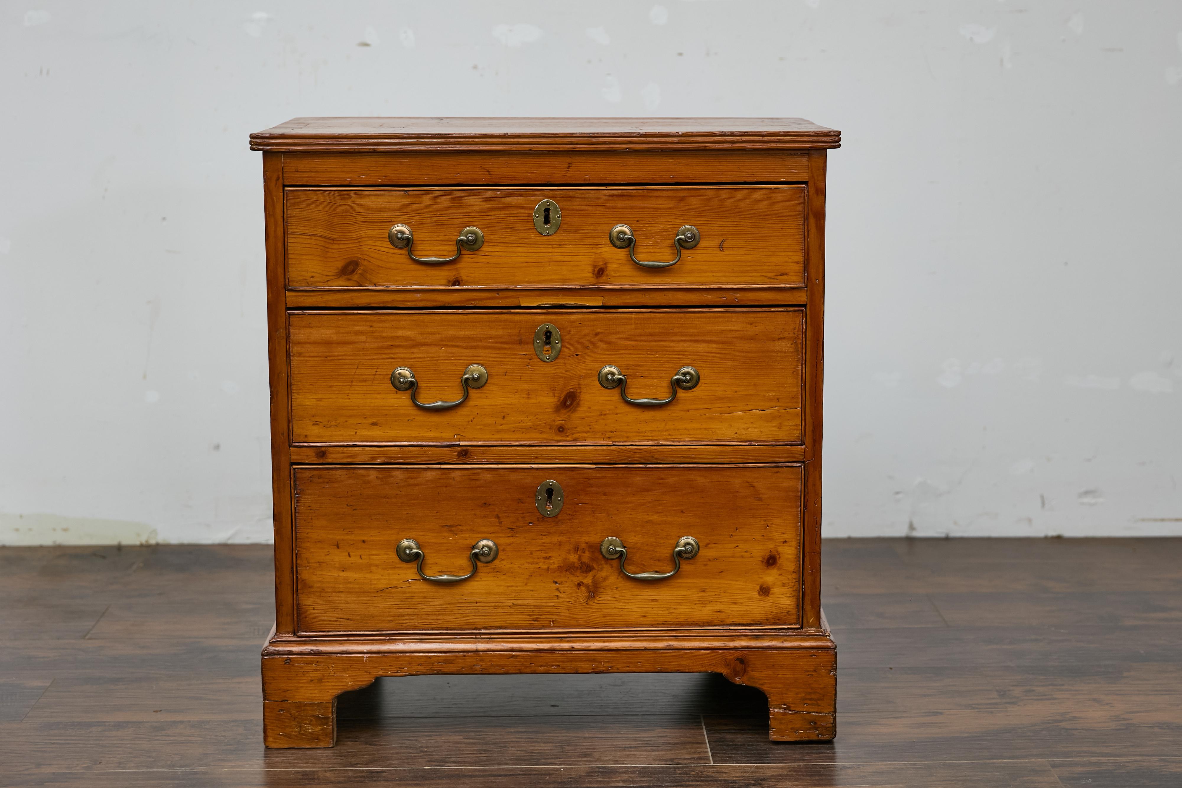 An English pine chest from the 19th century with three graduating drawers and brass hardware. This English pine chest from the 19th century embodies understated elegance with its three graduating drawers and simple yet refined design. Each drawer is