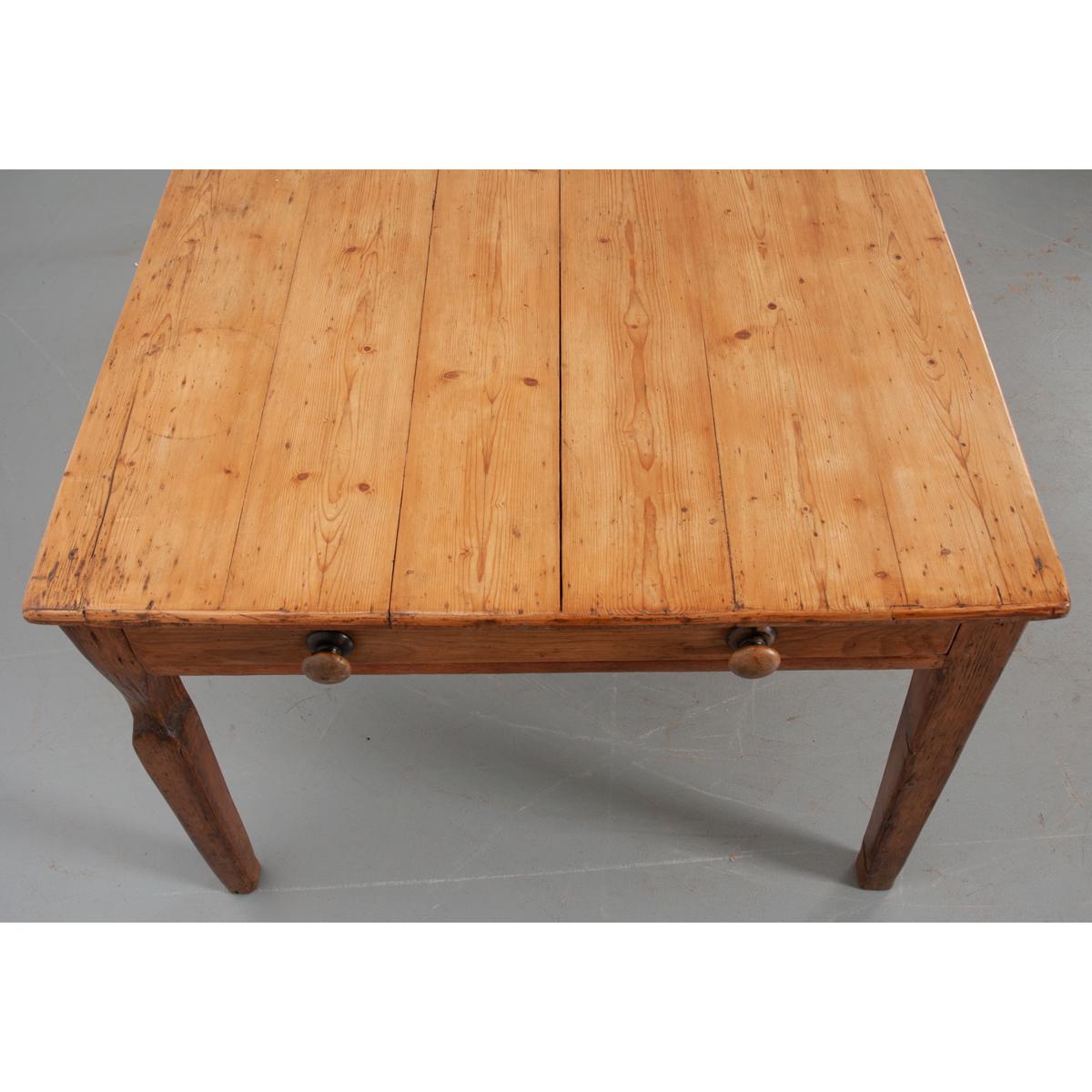 This is an English 19th century pine dining table. The wide and deep top sits over an apron with a large drawer on each end. The drawers have two turned wood knobs each. This table has a wonderful patina and is circa 1870.