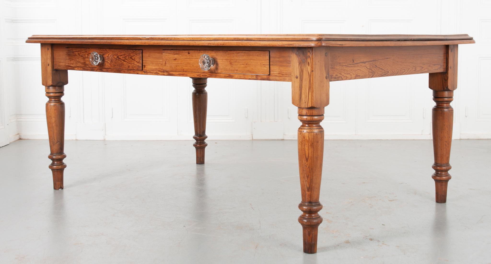A large, lovely and quintessentially English pine farmhouse table, dating to the 19th century and outfitted with two large drawers. Made of solid pine, the wood used to make this farm table has wonderfully expressive grain and a warm tone that will