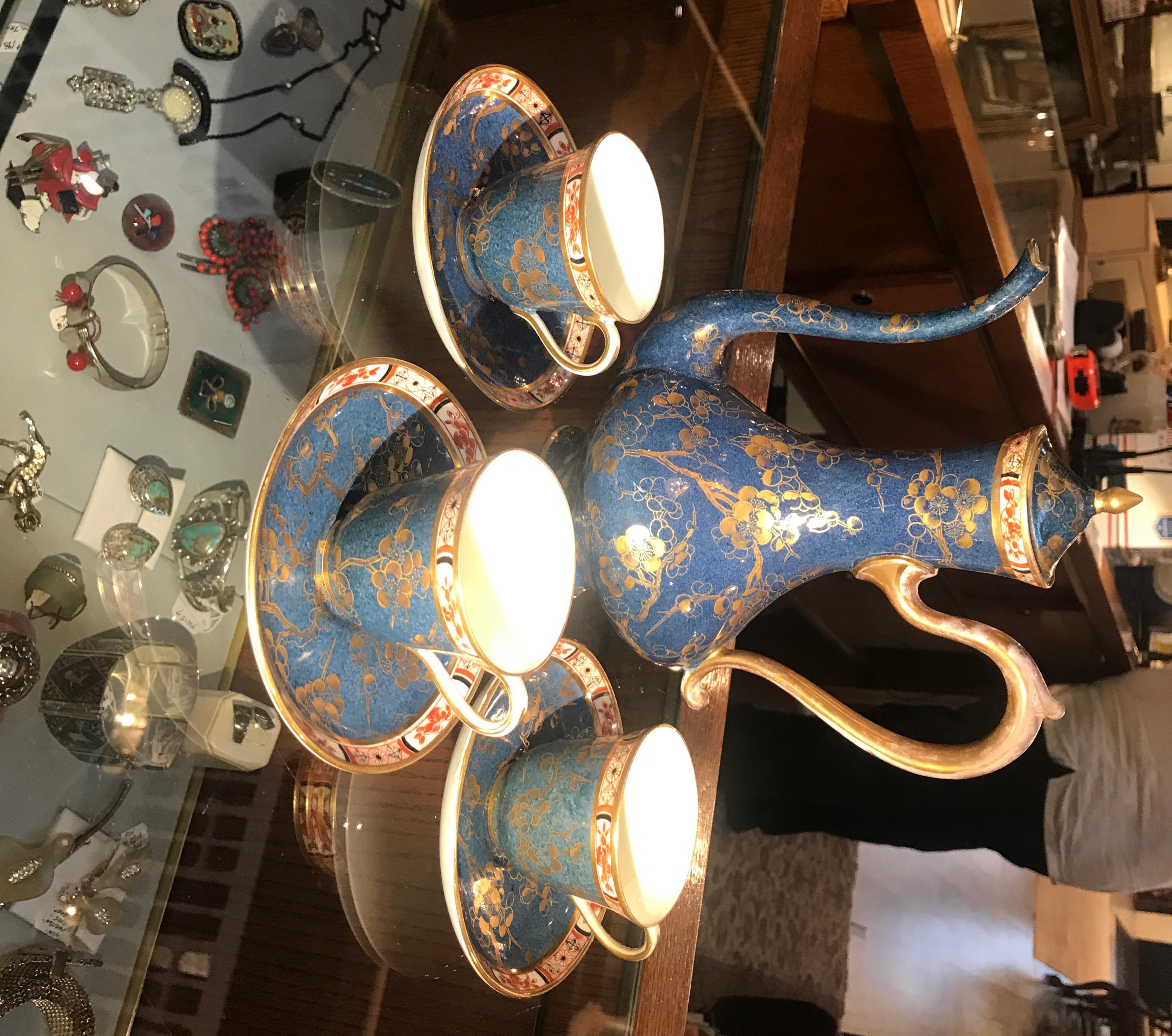 Hand painted deep blue English porcelain tall tea pot with three small espresso sized cups and saucers. The set with hand painted chinoiserie borders with a gilt overlay of cherry blossom branches. Marked on bottom Royal Crown Staffordshire, England.