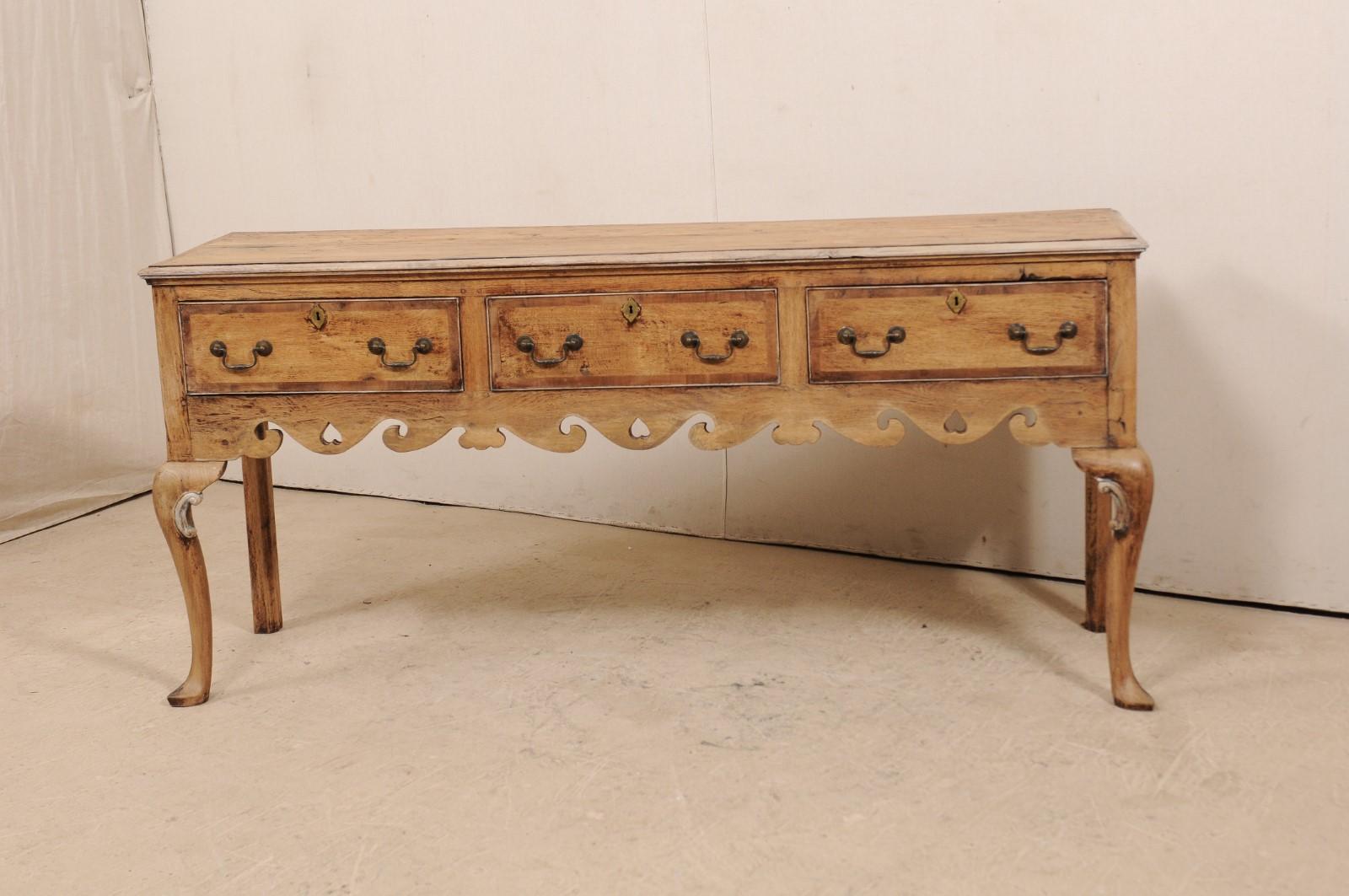 An English 19th century Queen Anne console with drawers. This antique English console table features a long, rectangular-shaped top, and houses three good-sized drawers, all set side-by-side, offering plentiful storage. The skirt is elaborately