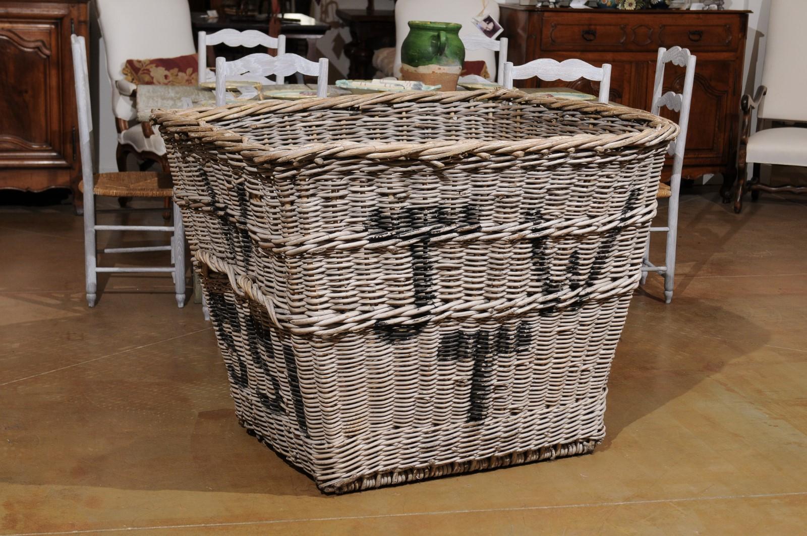 A large English reclaimed wicker mill basket from the 19th century, with weathered appearance. Born in England during the 19th century, this large rustic wicker baskets features a rectangular tapering shape, topped with a twisted trim. Presenting a