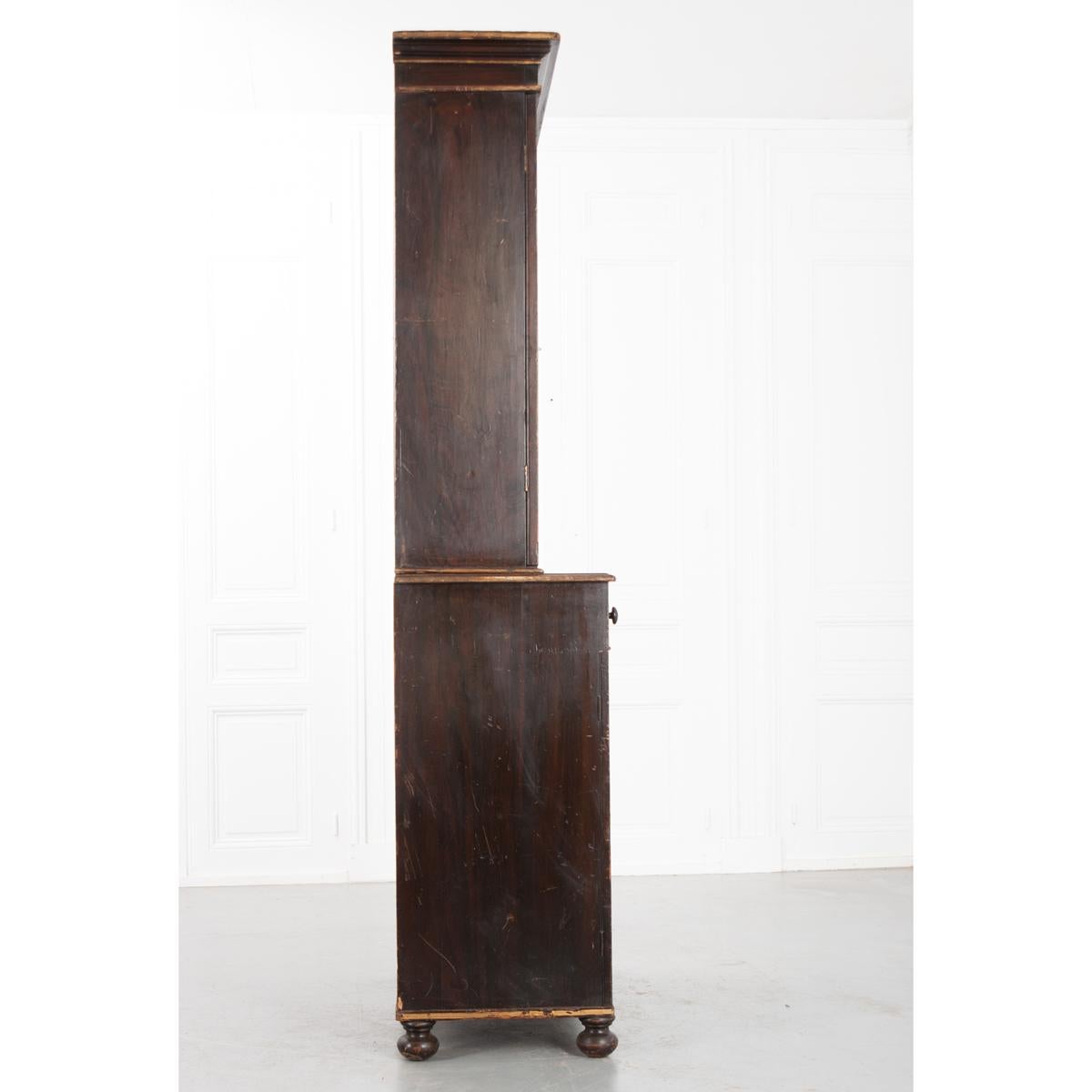 A warm and rich four door faux bois bookcase with a wonderful distressed quality, c. 1890. This painted piece features accented details in the mouldings and trim. The top section has two divided light, glass-front locking and latching doors that