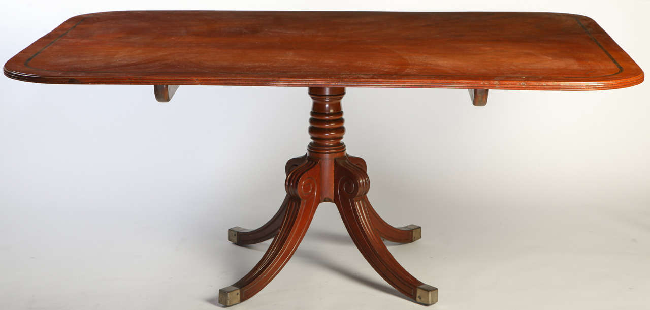 A Regency mahogany breakfast-table with rounded rectangular
crossbanded tilt-top above a ring turned spreading column and a quadripartite base, brass caps.
Measures: cm 180 x 125 x 76.
