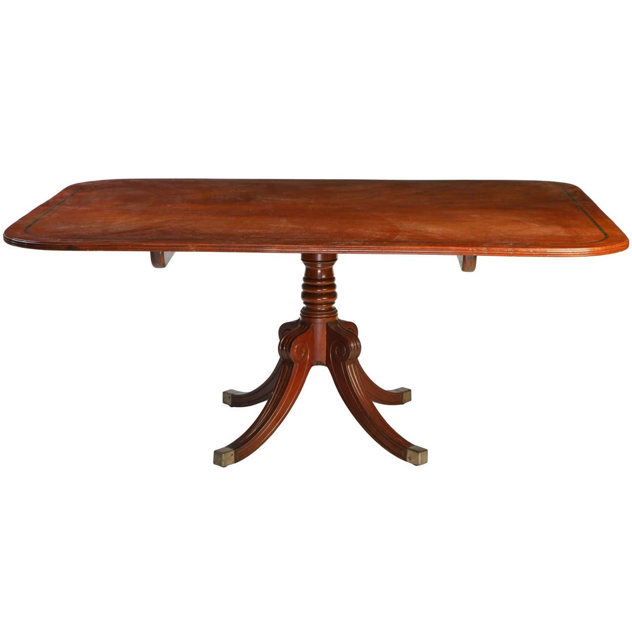 A Regency mahogany breakfast-table with rounded rectangular
crossbanded tilt-top above a ring turned spreading column and a quadripartite base, brass caps.
Measures: cm.180 x 125 x 76.