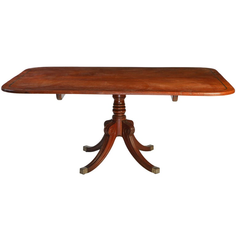A Regency mahogany breakfast-table with rounded rectangular
crossbanded tilt-top above a ring turned spreading column and a quadripartite base, brass caps.
Measures: cm.180 x 125 x 76.