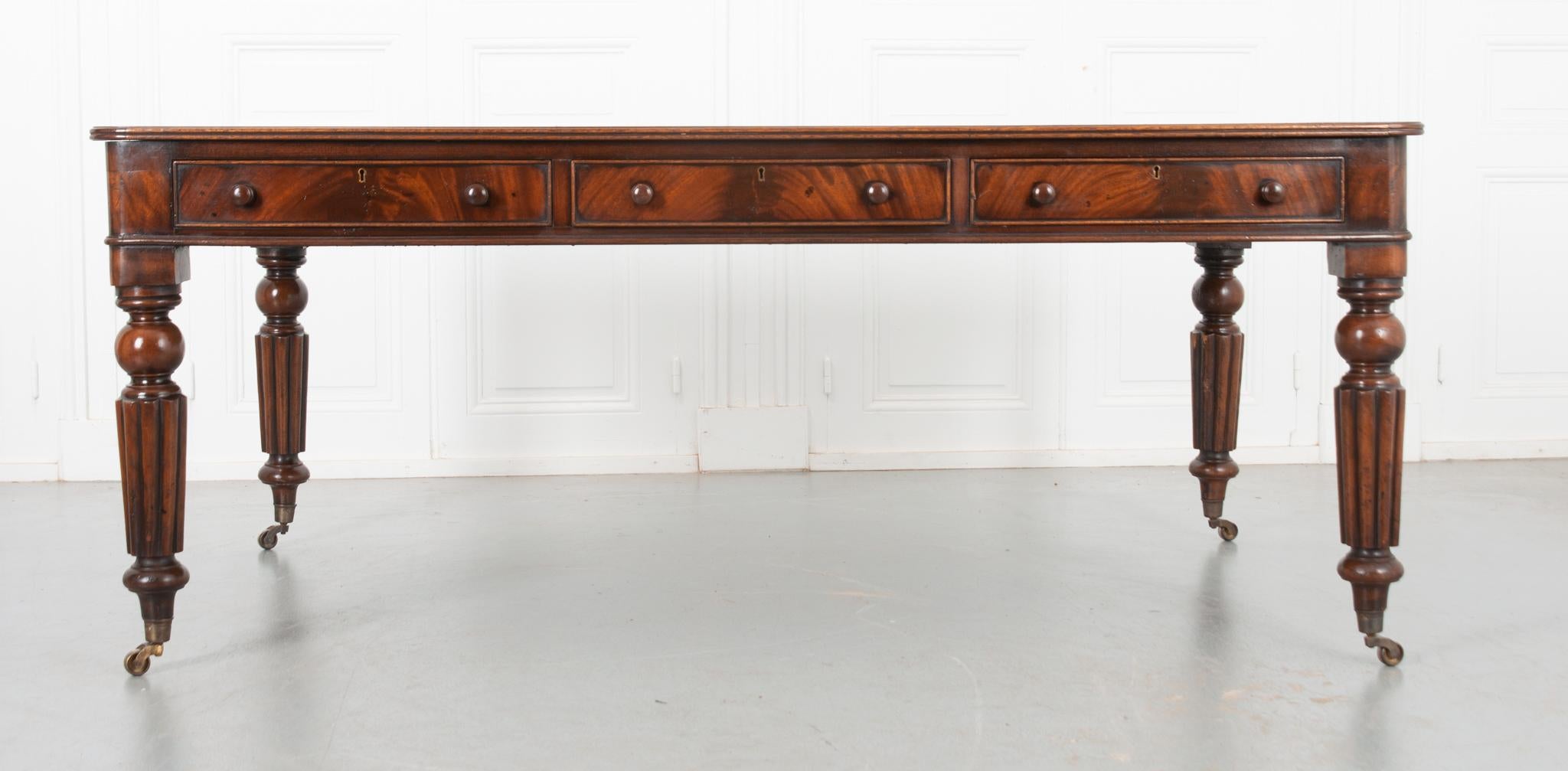 This fine Regency partners desk comes from England, circa 1900. The whole is made of beautiful mahogany with a work surface made of worn green leather. The perimeter of the stunning leather has been imprinted with two rows of decorative leafy