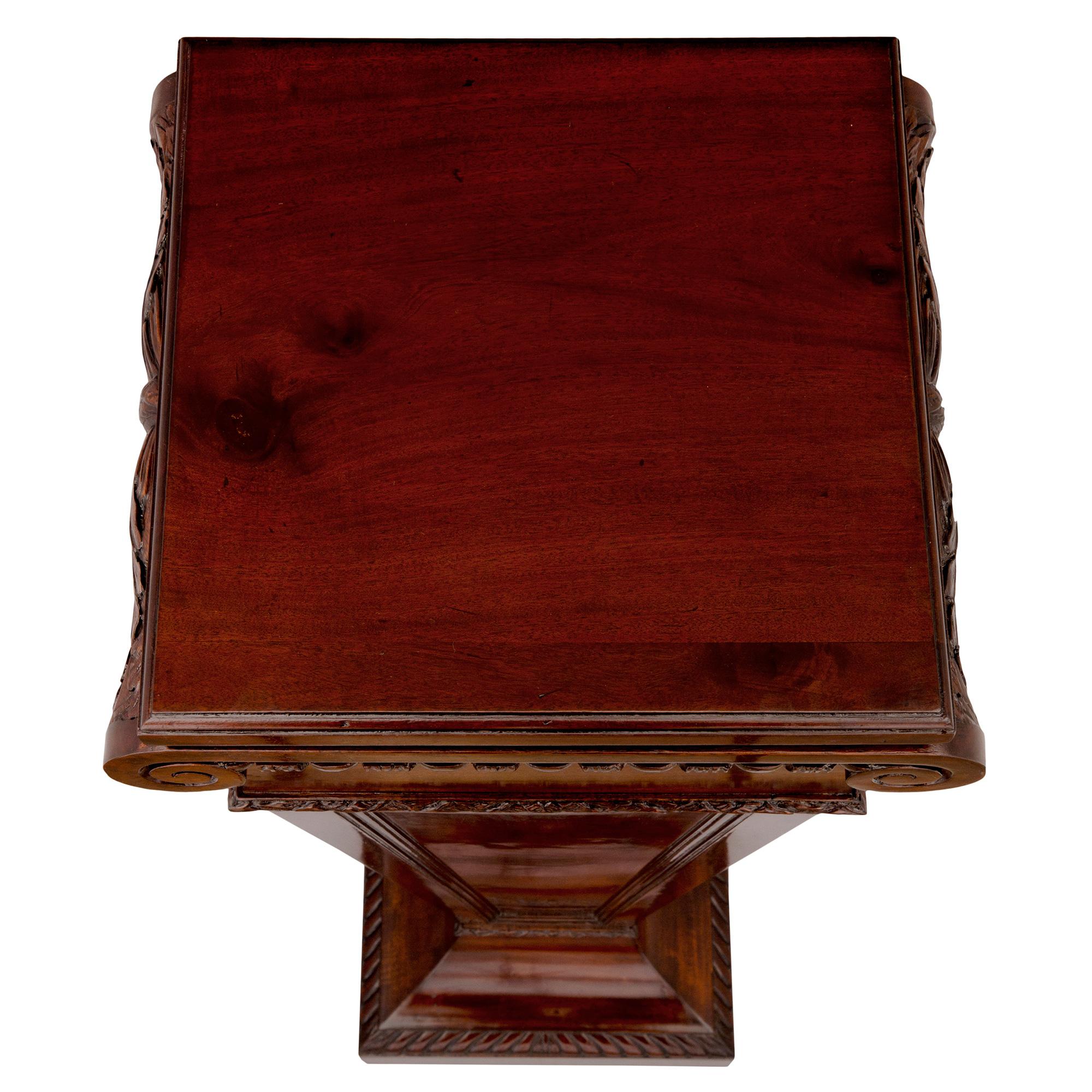 An elegant English 19th century Regency style mahogany pedestal column. The pedestal is raised by a square base with a finely carved wraparound gadroon design. Above the lightly curved socle shaped plinth is the square tapered central support with