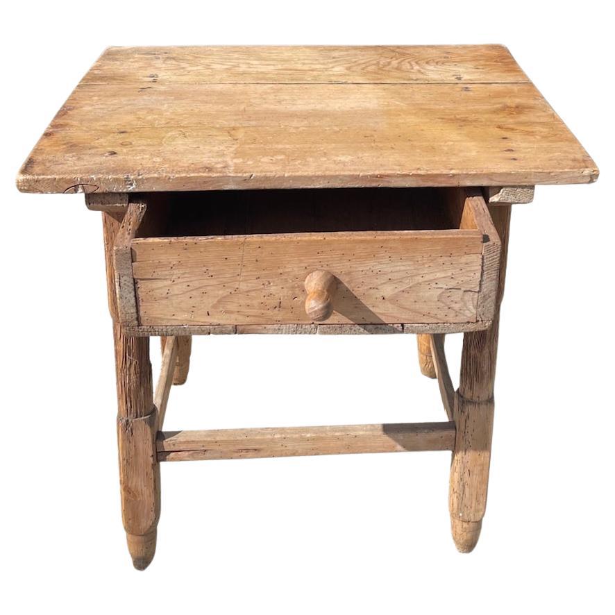 This is a good example of a rustic pine 19th Century end table with a centre drawer and hand-carved legs.
