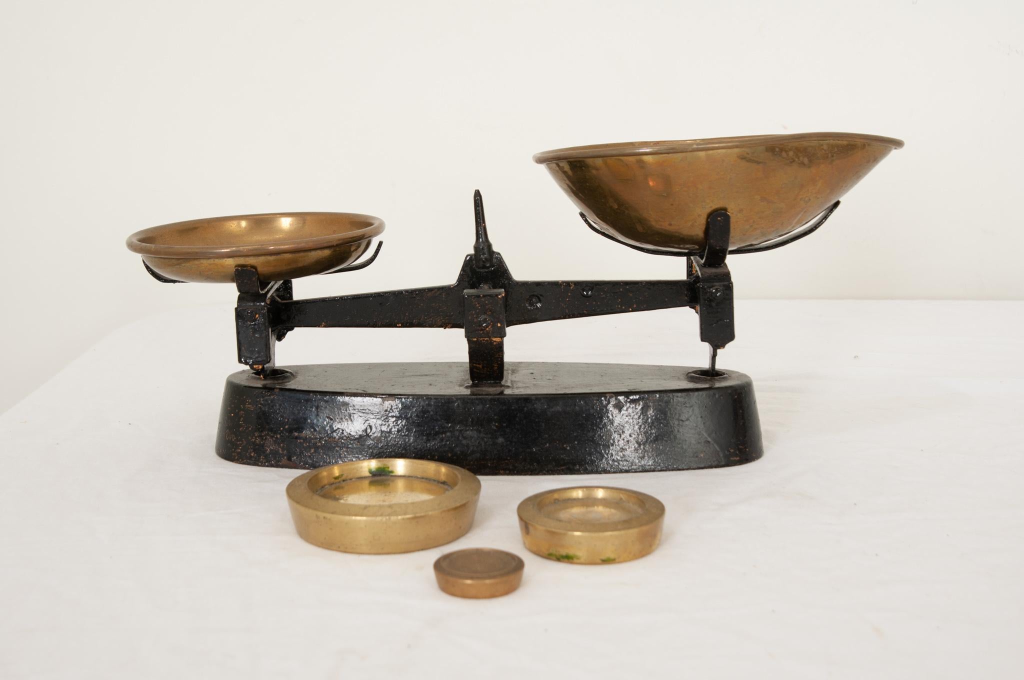 An antique British counter or grocer scale in cast iron and brass circa 1890. Small scales of this type had many uses during the Victorian Era and could be found in apothecaries, tobacconists, grocers, and shops. This scale has a painted black cast