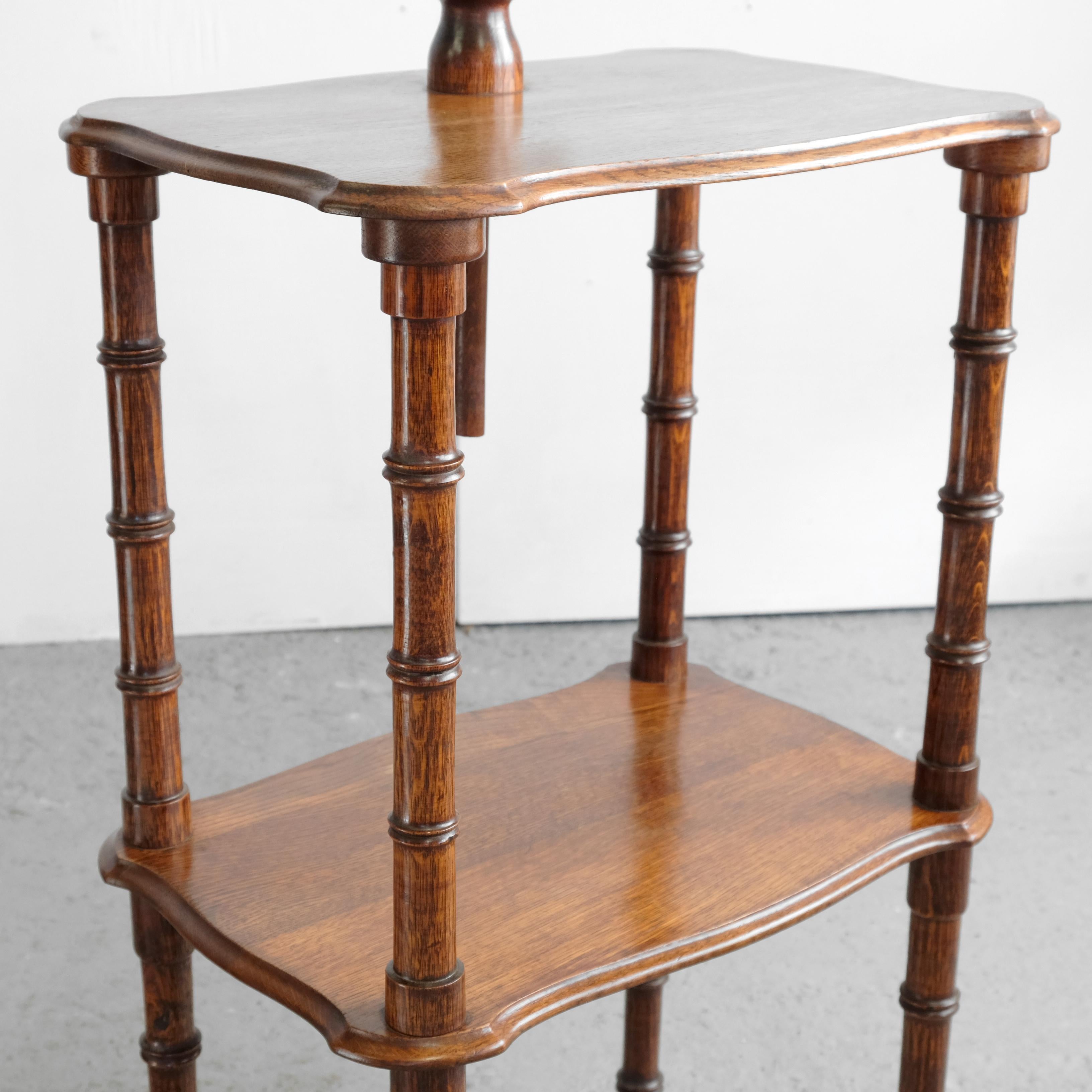 A 19th-century English oak shaving stand. Faux bamboo turned legs, supporting two shaped tiers, the upper having a height-adjustable, tilting and swivelling mirror with two swing-out candle sconces with brass liners. The mirror section turnings are