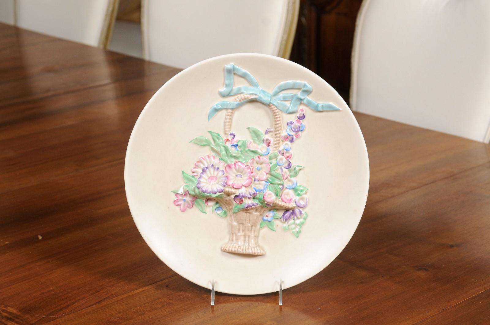 An English porcelain hanging plate from the 19th century, depicting a ribbon tied wicker floral basket and signed Clarice Cliff, Newport Pottery England in the back. Created in England during the 19th century, this porcelain hanging plate, created