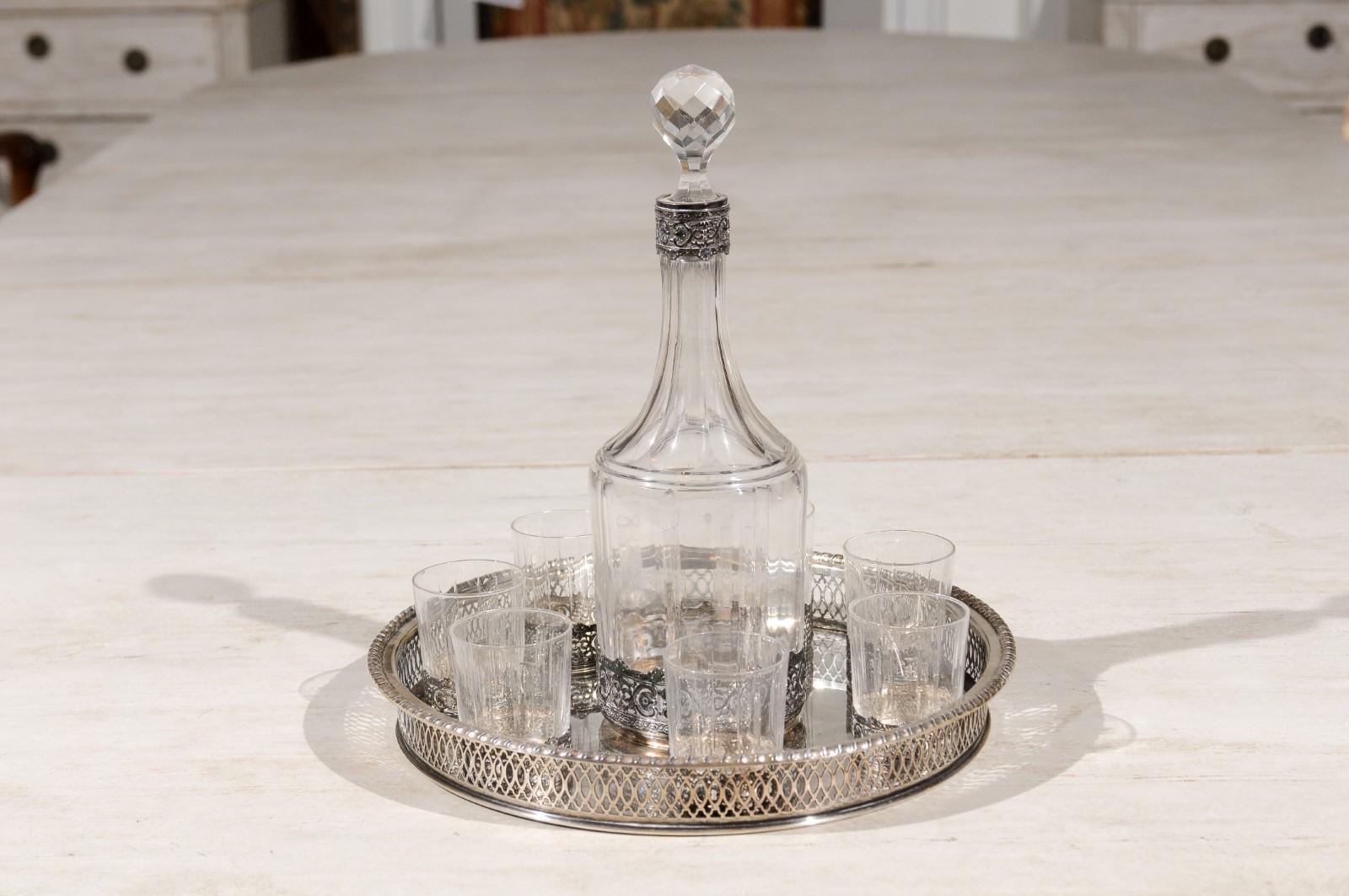 An English silver and crystal decanter set from the 19th century, with seven glasses, a decanter and silver platter. Born in England during the 19th century, this exquisite set features a 3.5 inches diameter x 10.75 inches high crystal decanter,