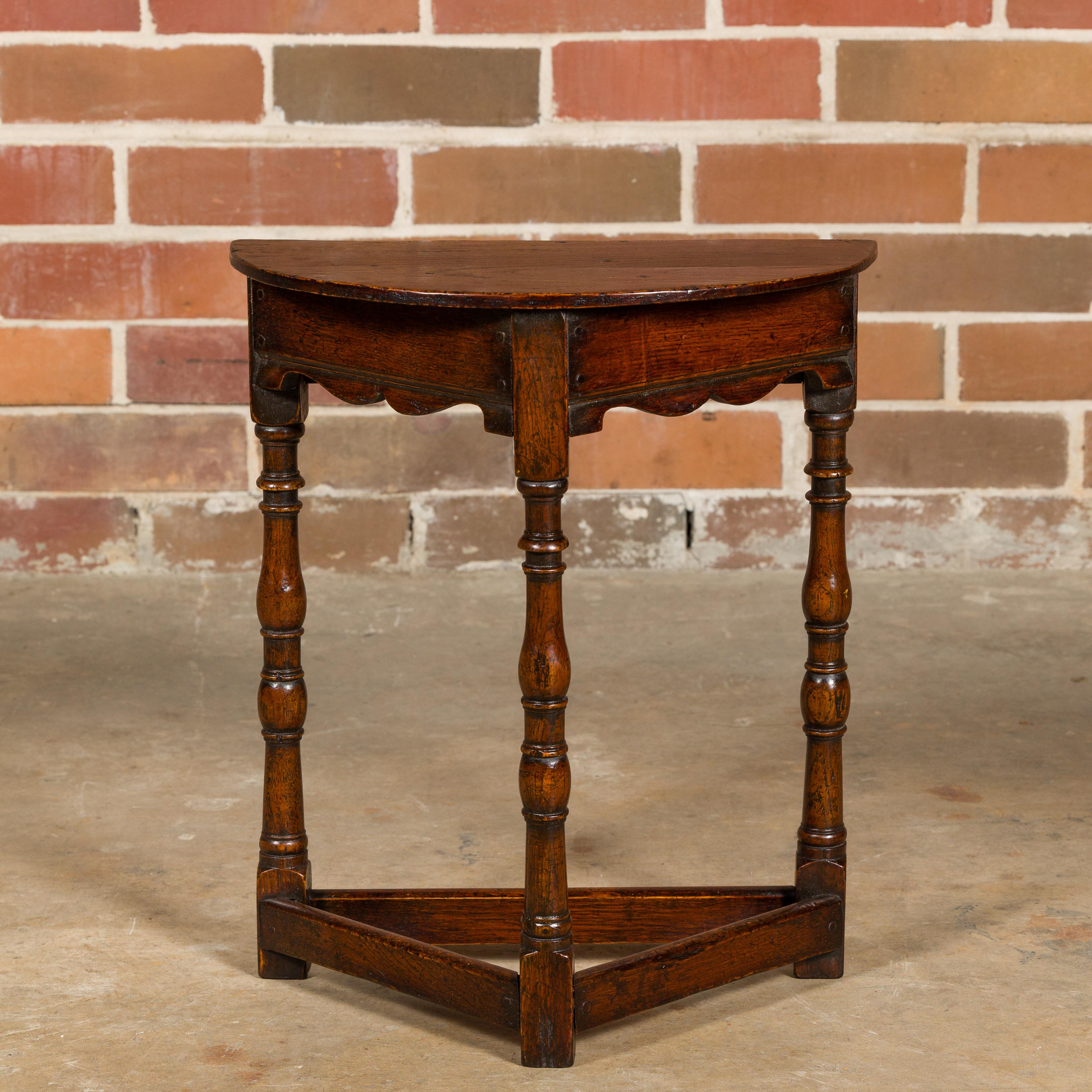 This charming English oak demi-lune side table from the 19th century is a beautiful blend of classical design and rustic appeal. Its small, half-moon shape makes it a versatile piece, perfect for adding a touch of antique elegance to a variety of