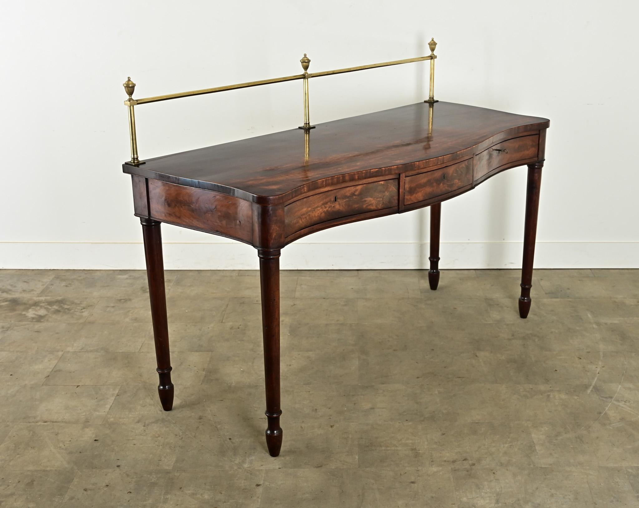 Incredibile server, o credenza, in mogano inglese risalente al XVIII secolo, proveniente da una grande tenuta di campagna. Un'alta ringhiera in ottone lungo il retro è sormontata da tre finials a urna immacolati. Il colore sorprendente aggiunge