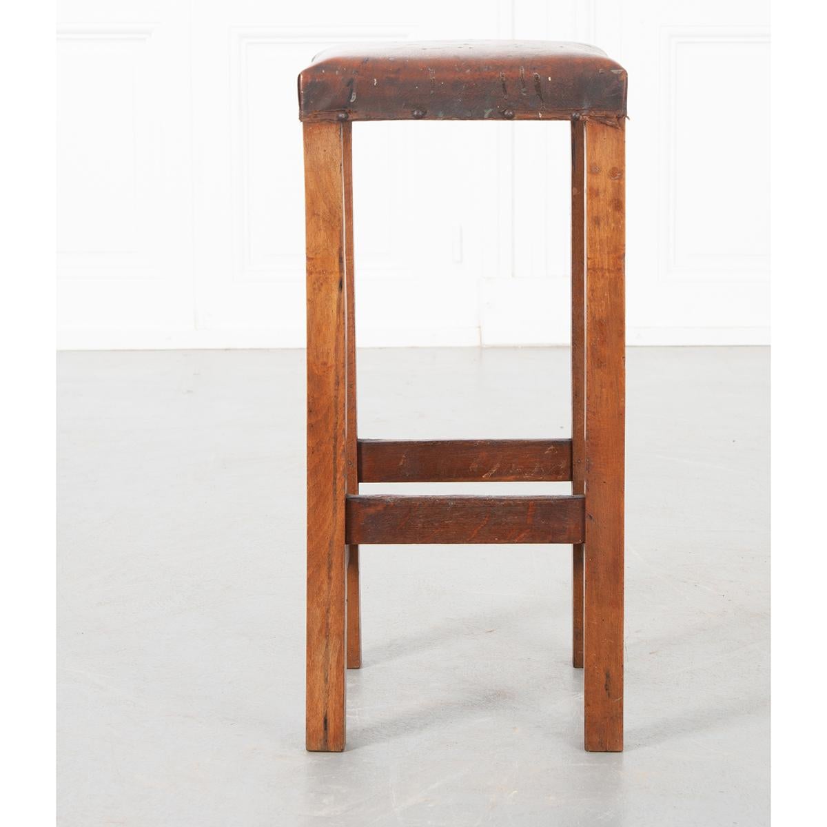 This is an English 19th century tall stool with simple straight legs and stretchers. The wood is walnut and the seat is upholstered. Circa 1890.