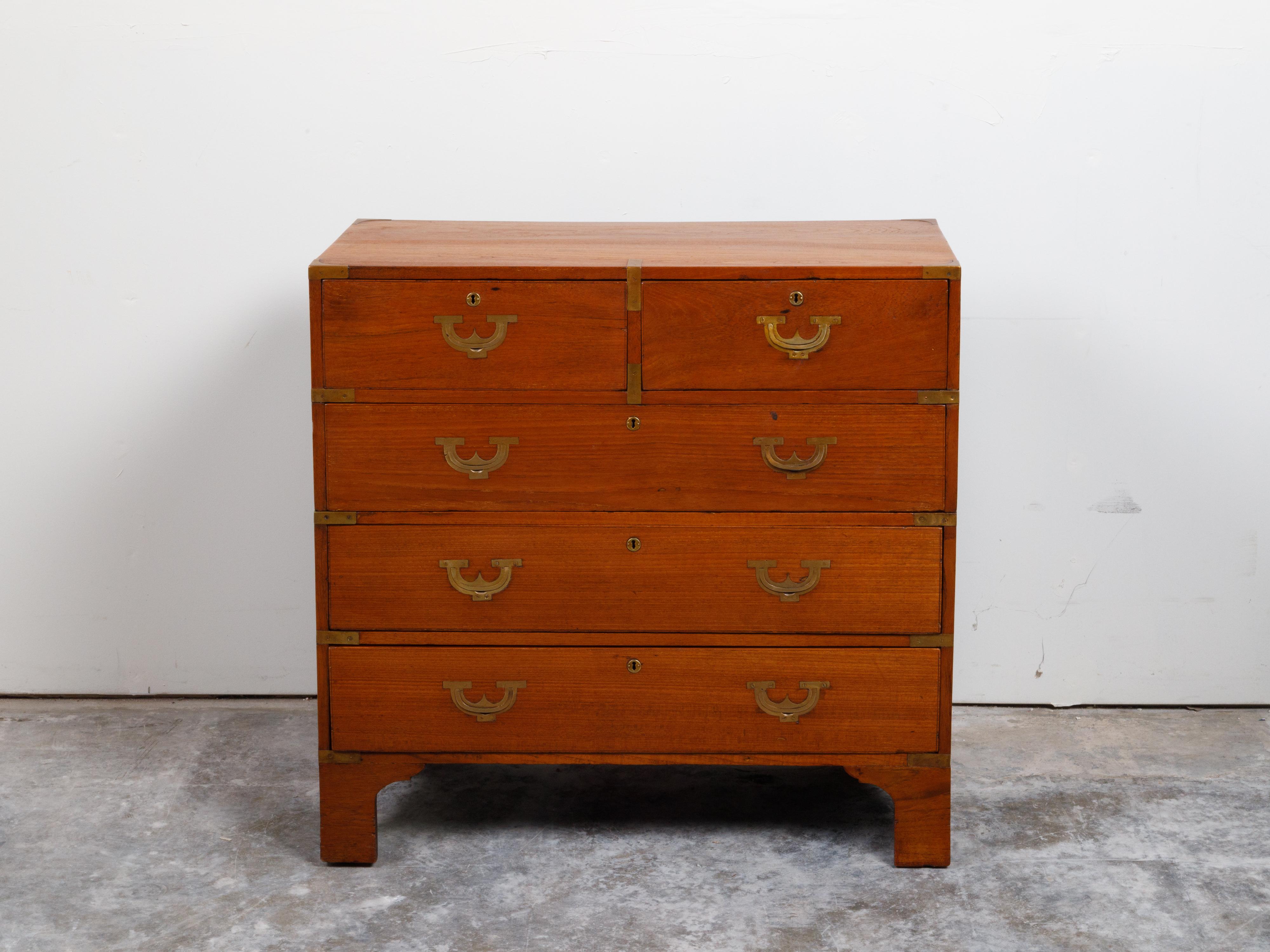 An English Campaign teak wood chest from the 19th century, with brass hardware and bracket feet. Created in England during the 19th century, this teak wood chest features a rectangular top with brass accents, sitting above two small dovetailed