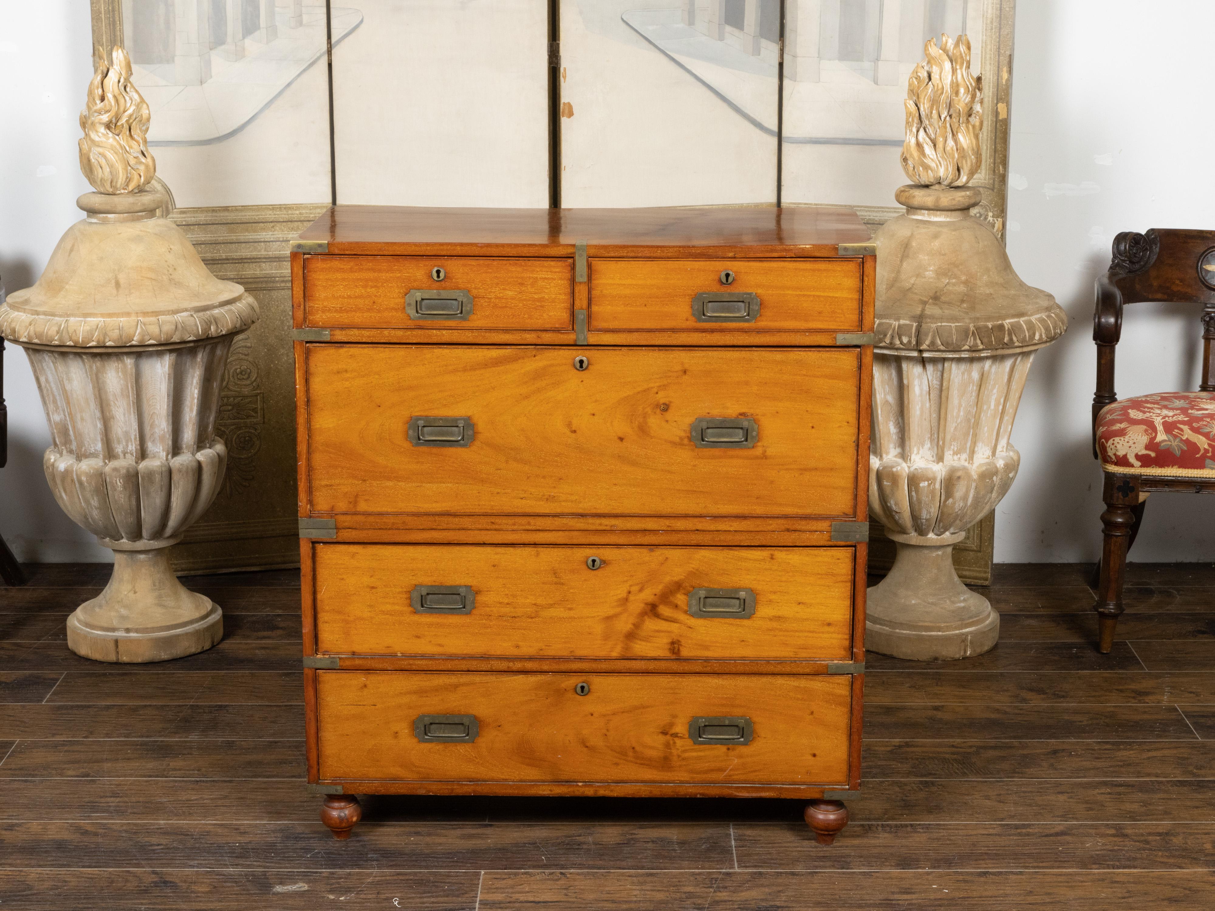 An English teak wood two-part campaign chest from the 19th century, with five drawers, inset brass hardware and turnip feet. Created in England during the 19th century, this teak (a very sturdy wood) campaign chest is made of two parts stacked on