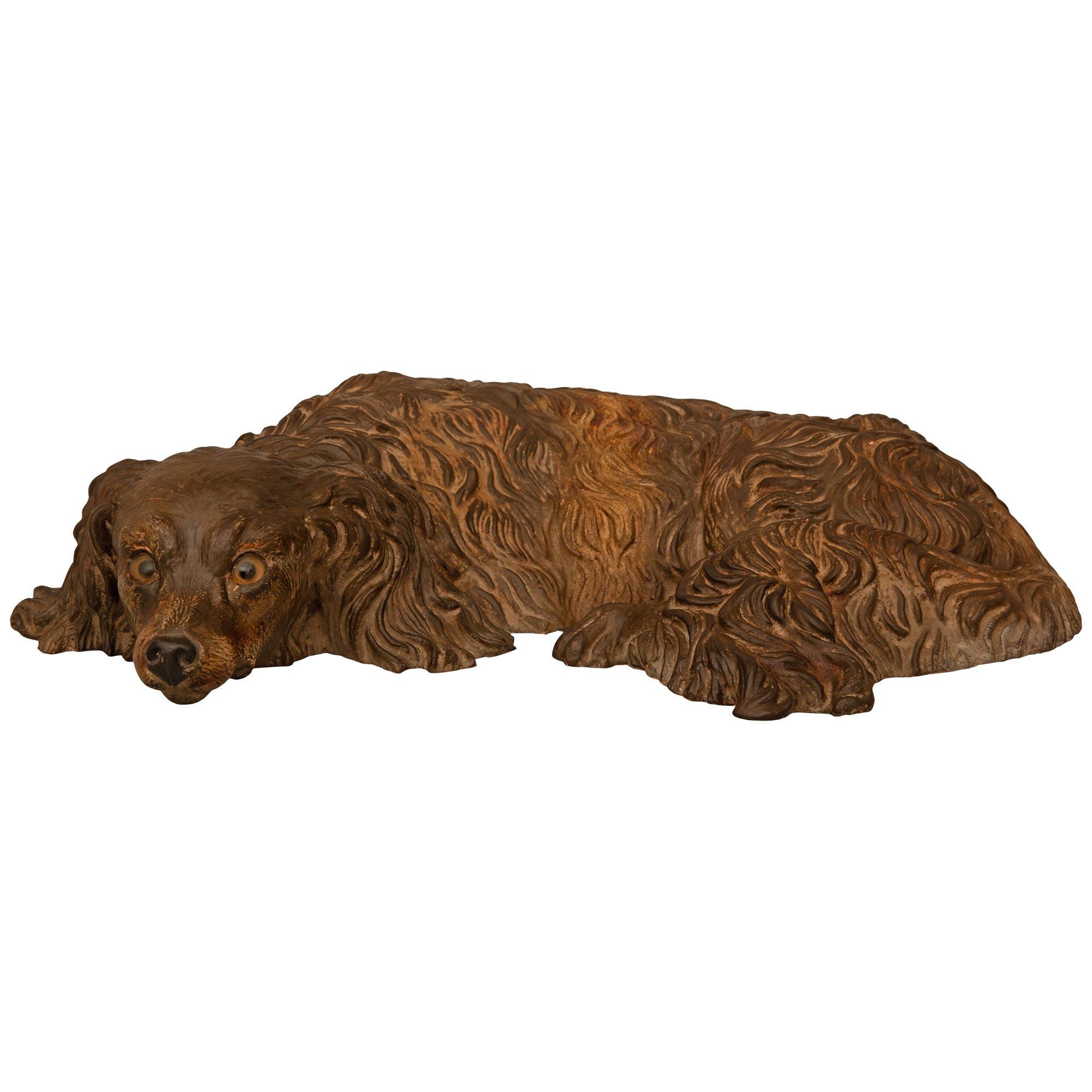 A wonderfully decorative and most charming English 19th century Terra Cotta earthenware statue of a dog. The small English Spaniel is laying down with an exquisite expression and fur all spread out. The dog has a welcoming gaze and exceptional
