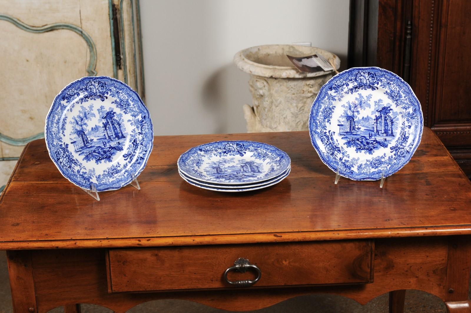 Six English blue and white transferware dinner plates from the 19th century, with classical ruins and floral motifs, sold individually. Born in England during the 19th century, each of these six blue and white dinner plates features a romantic