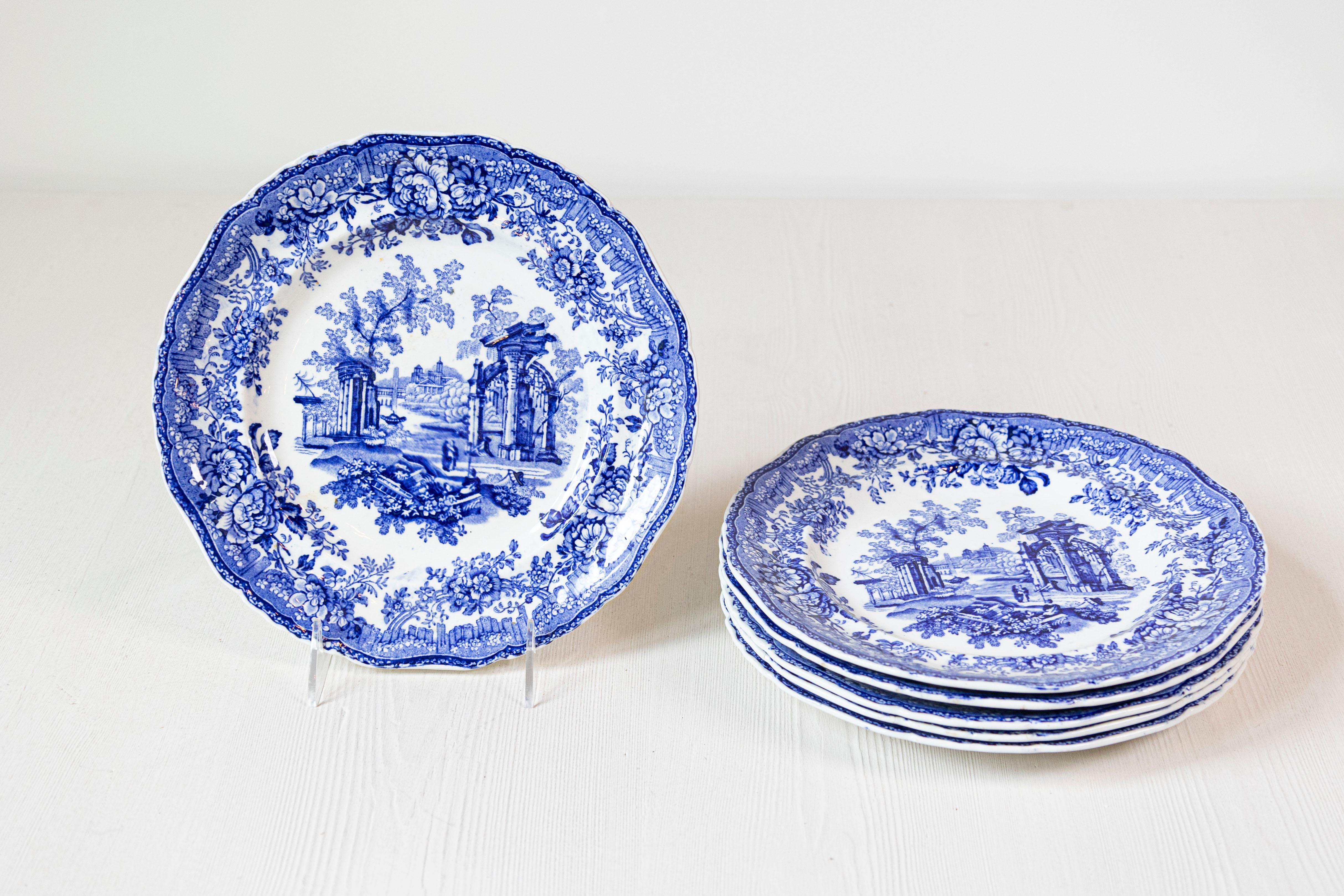 Six English blue and white transferware dinner plates from the 19th century, with classical ruins and floral motifs, sold individually. Born in England during the 19th century, each of these six blue and white dinner plates features a romantic