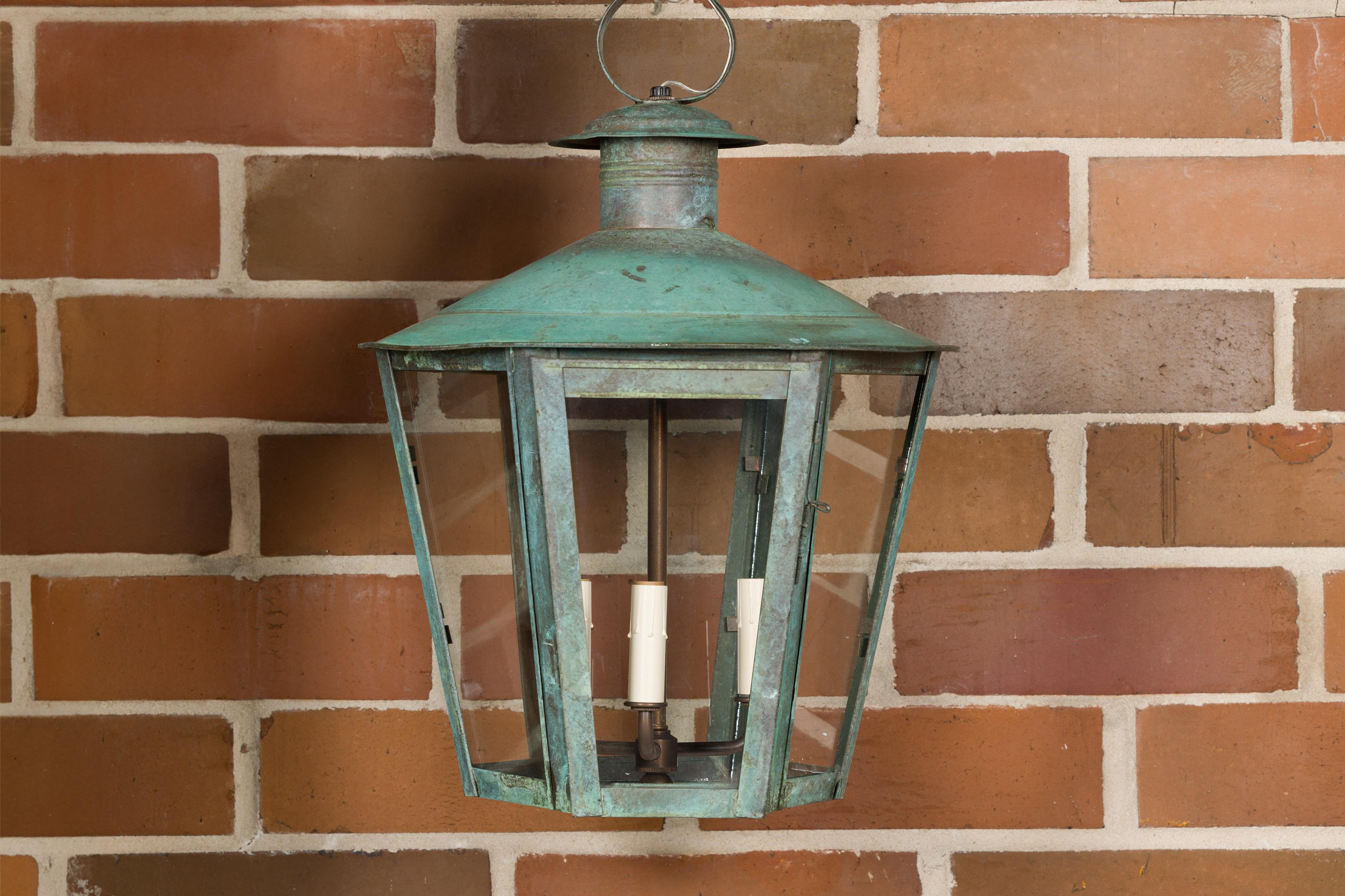 An English Victorian period copper lantern from the 19th century with three lights and glass panels. This exquisite English Victorian copper lantern, dating back to the 19th century, is a captivating blend of timeless elegance and functional design.