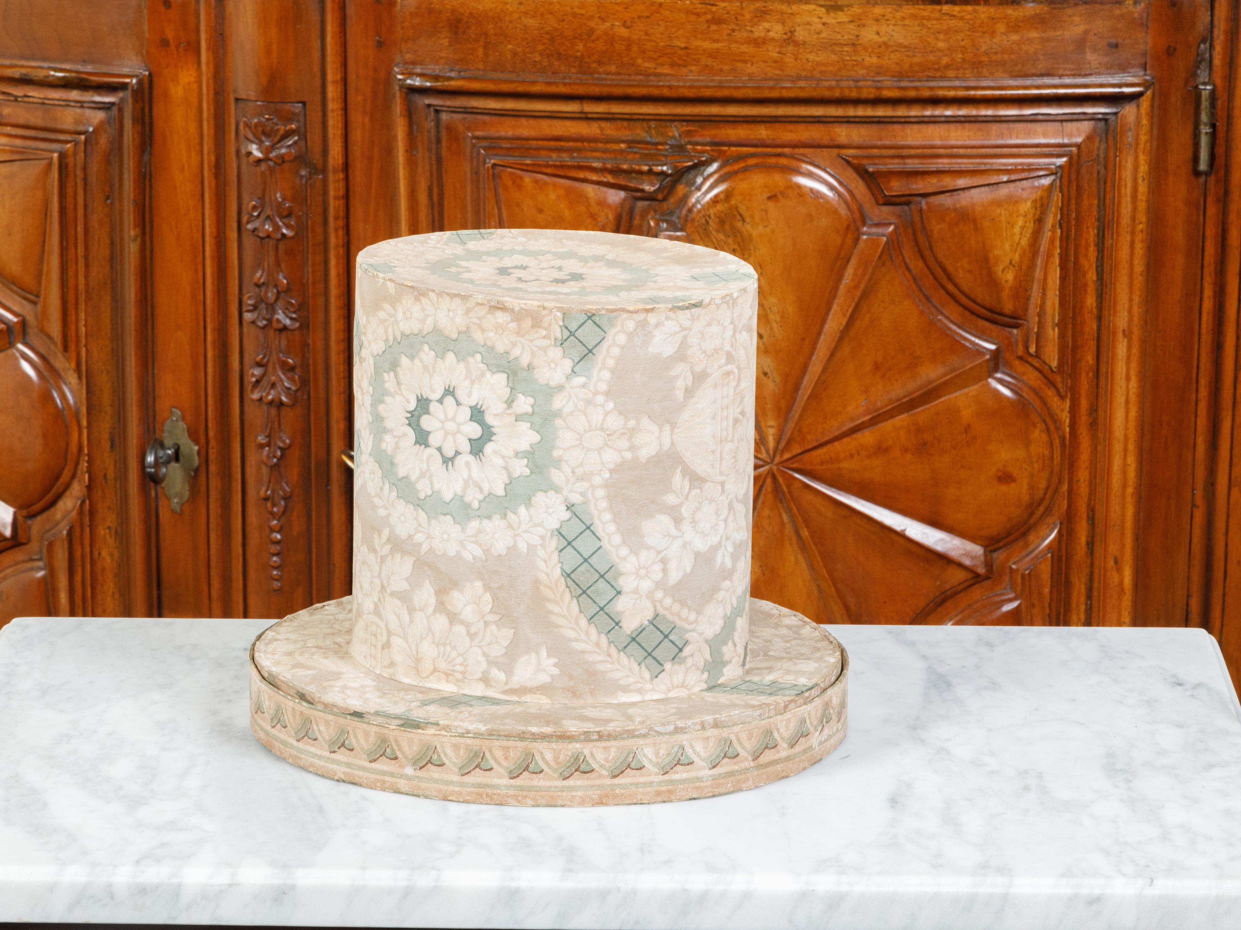 An English Victorian period paper hat box from the 19th century, with floral motifs and book pages. Created in England during the reign of Queen Victoria, this hat box features a floral-themed top opening to reveal a book covered interior. An