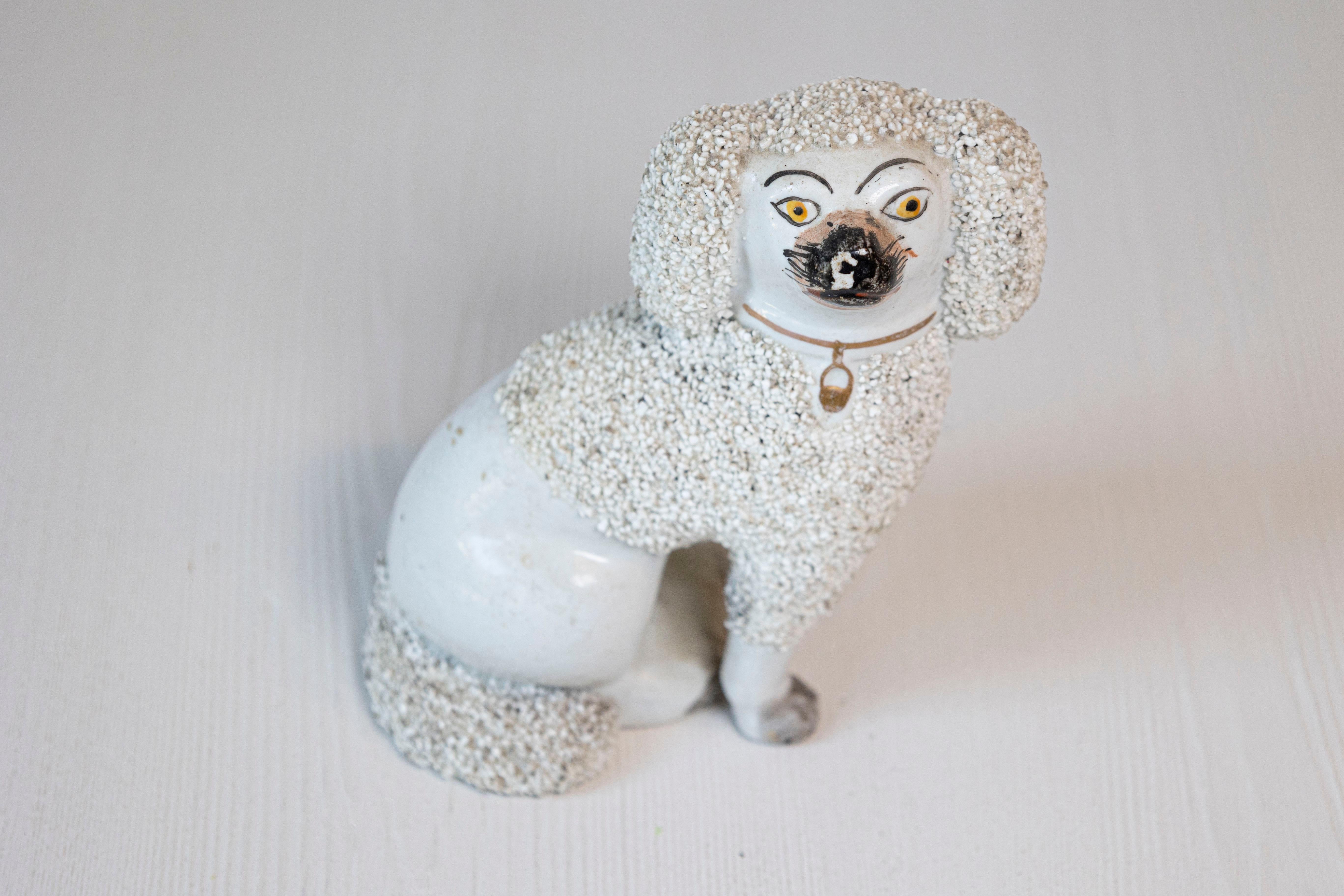 An English Victorian period slit leg Staffordshire dog from the 19th century with textured coat and gilded collar. Created in England during the reign of Queen Victoria, this Staffordshire dog features a white-coated dog with textured areas,
