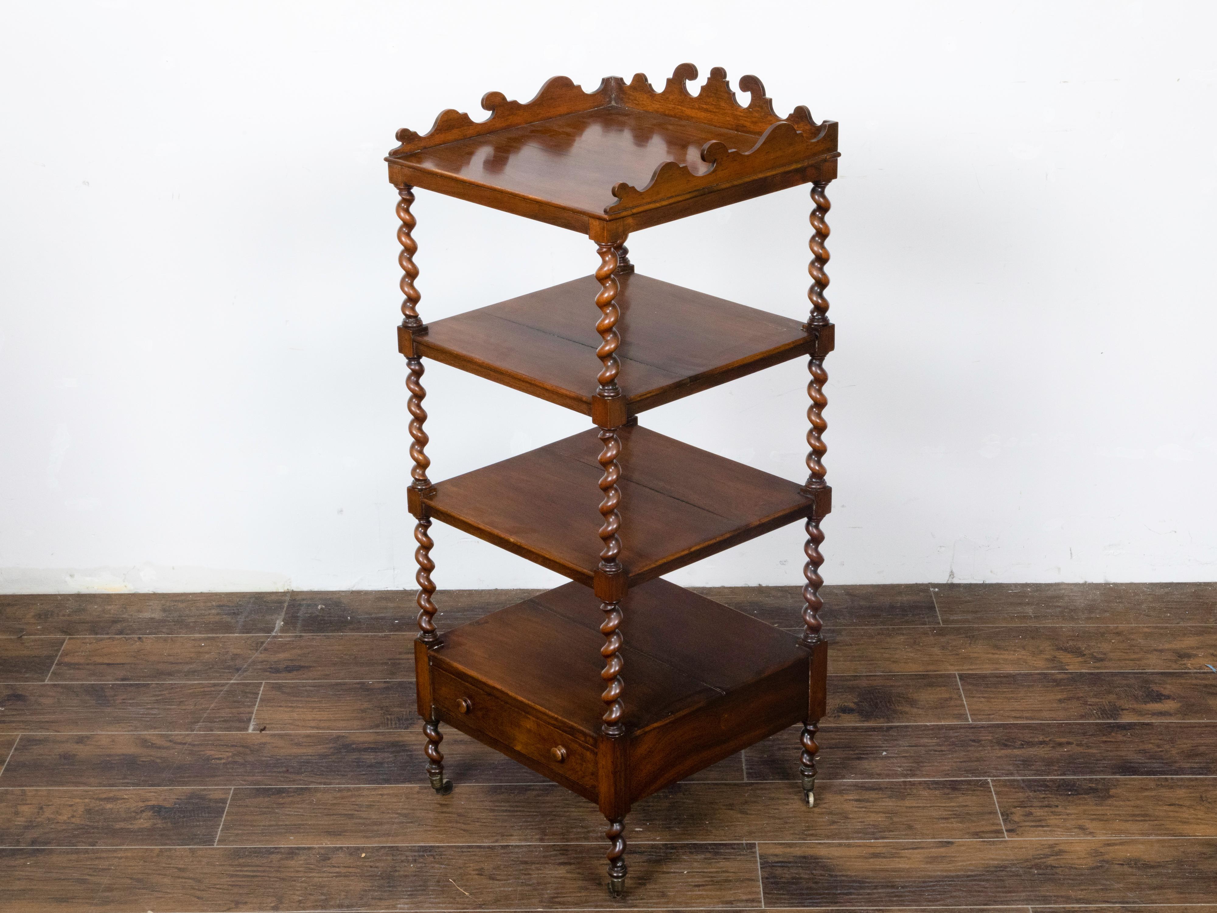 An English walnut barley twist four-tiered shelf with lower drawer, casters and carved three-quarter gallery at the top. Introduce the classic charm and functional elegance of this English walnut four-tiered freestanding shelf into your home, a